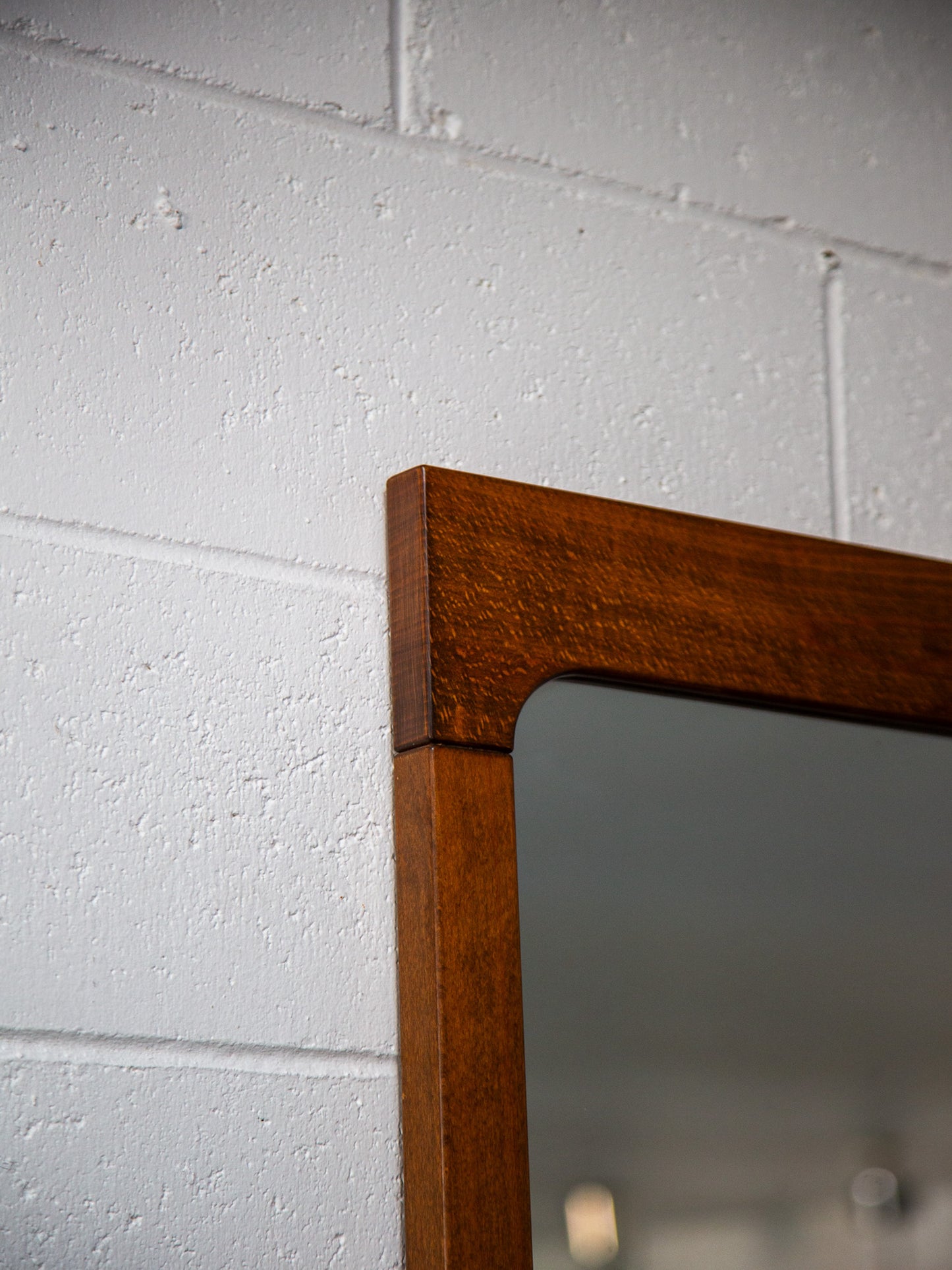 Wooden-framed mirror on a white brick wall