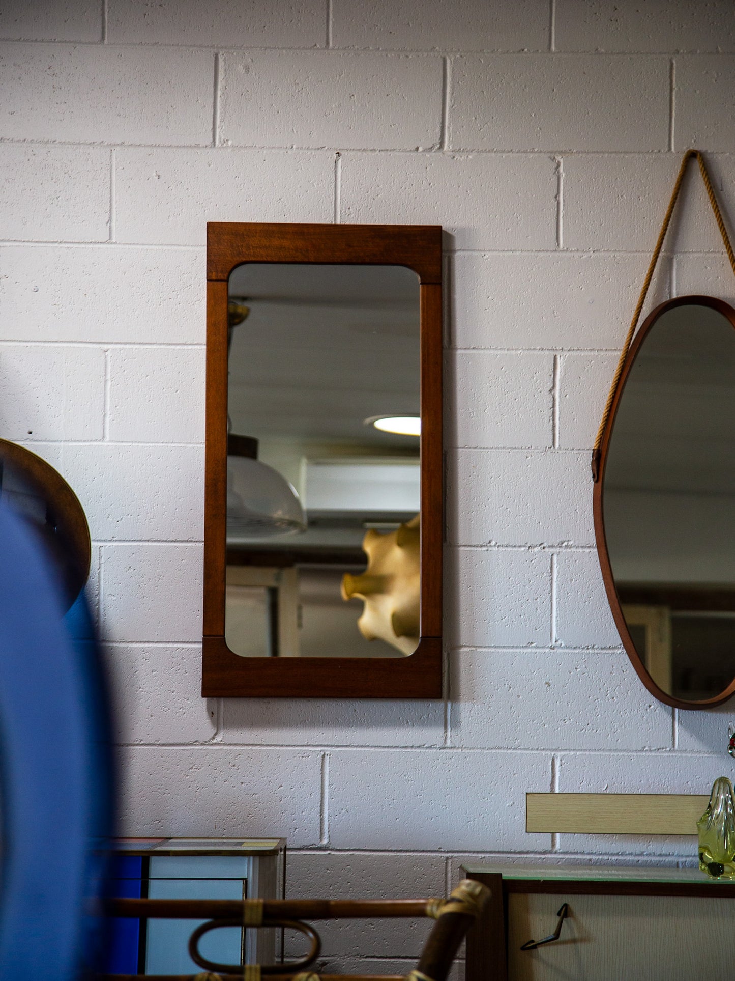 Wooden mirror on a white tiled wall with reflections.