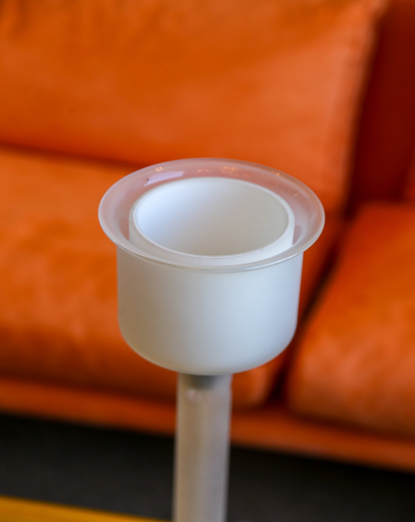 White plastic component on a stand against an orange sofa background