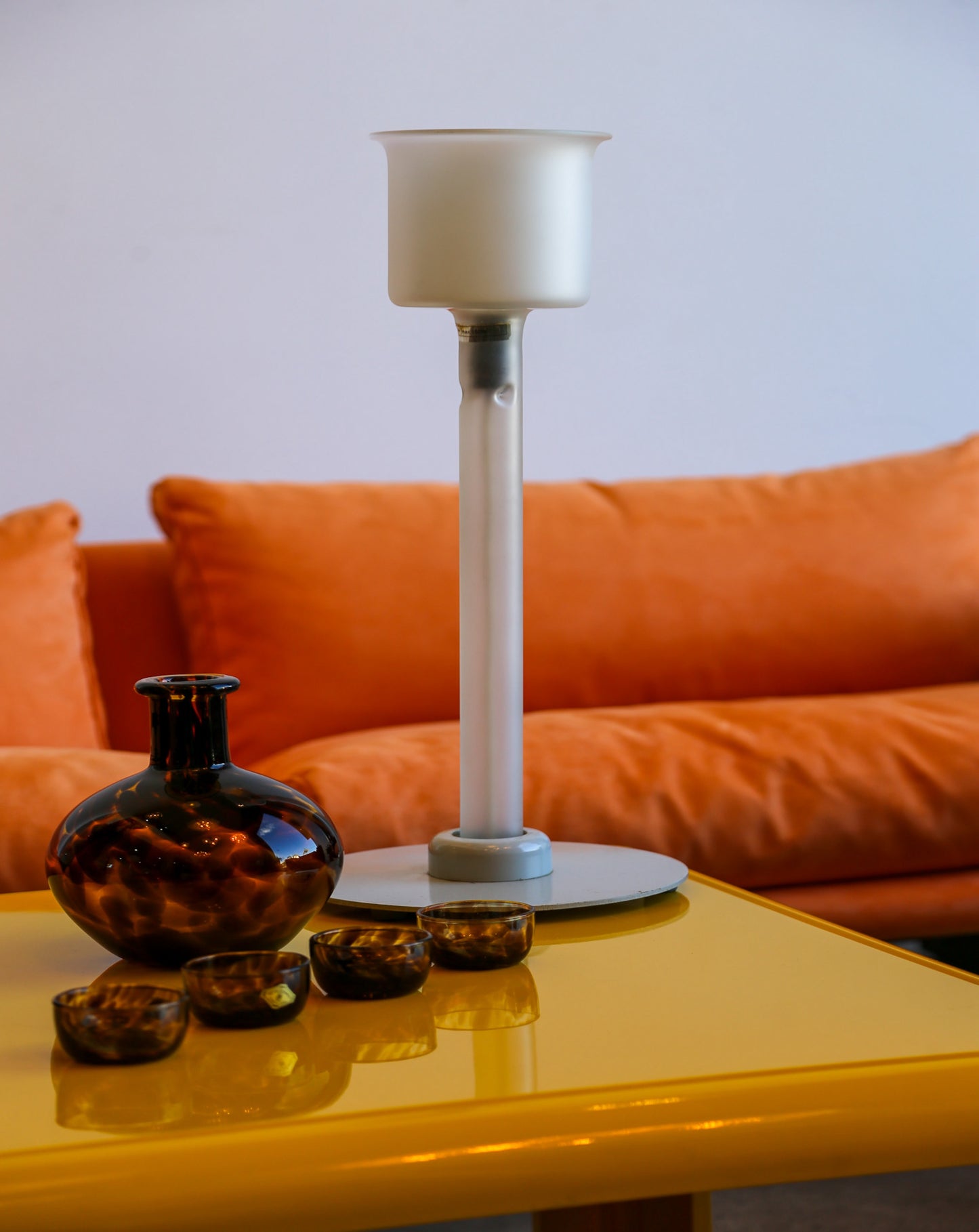 Decorative items on a yellow table with an orange sofa in the background