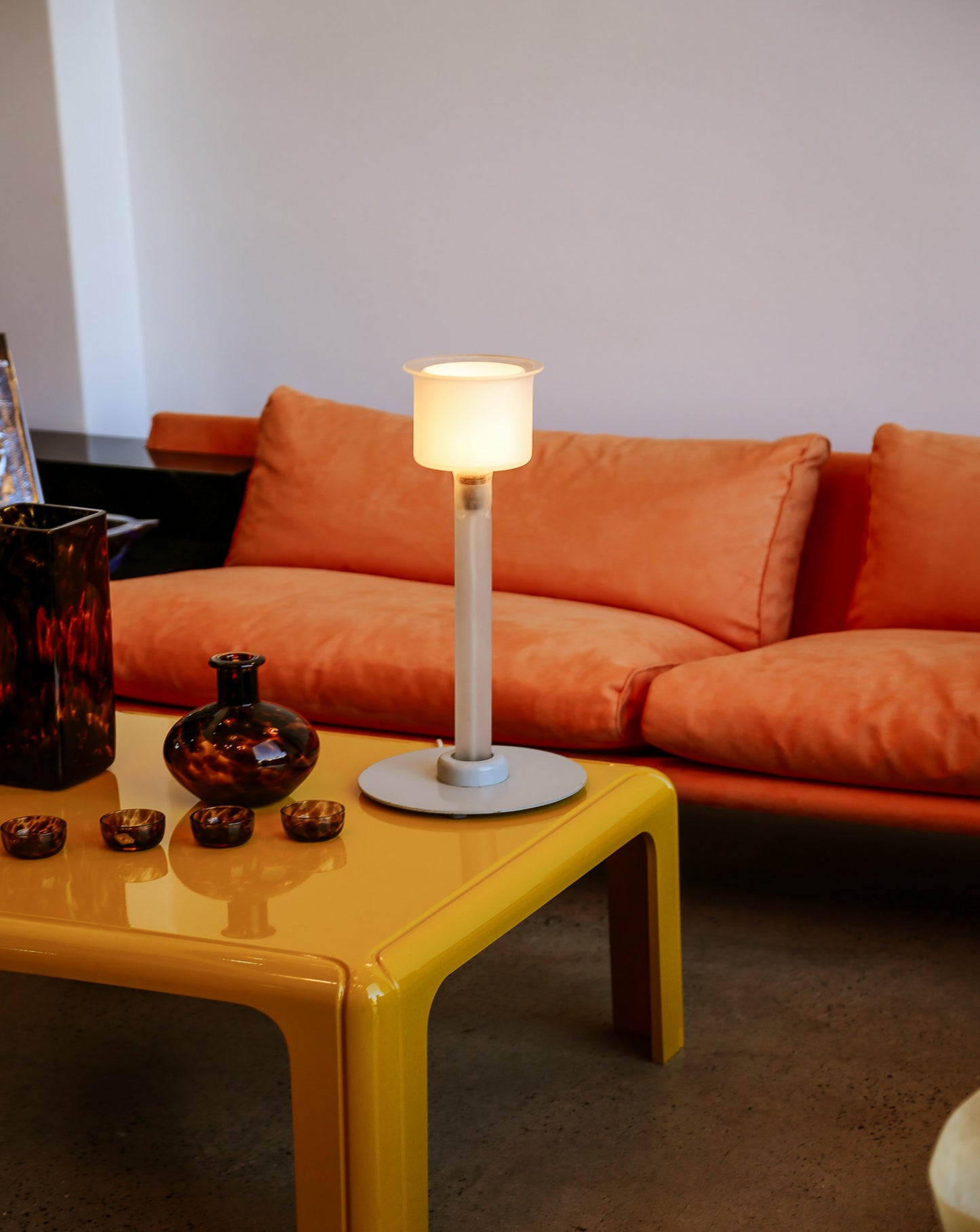 Orange sofa with a yellow coffee table and a lamp in a living room setting.