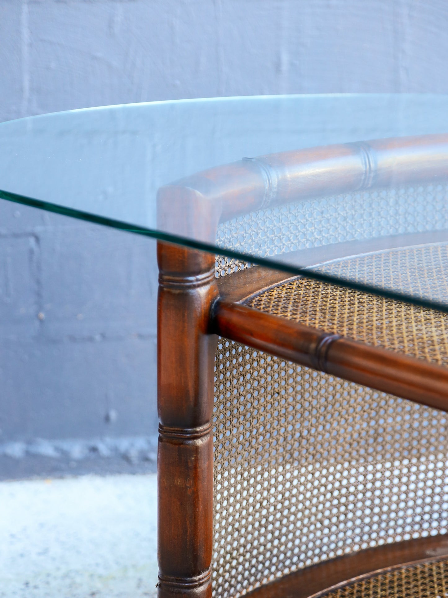 Glass-top table with rattan frame on a neutral background