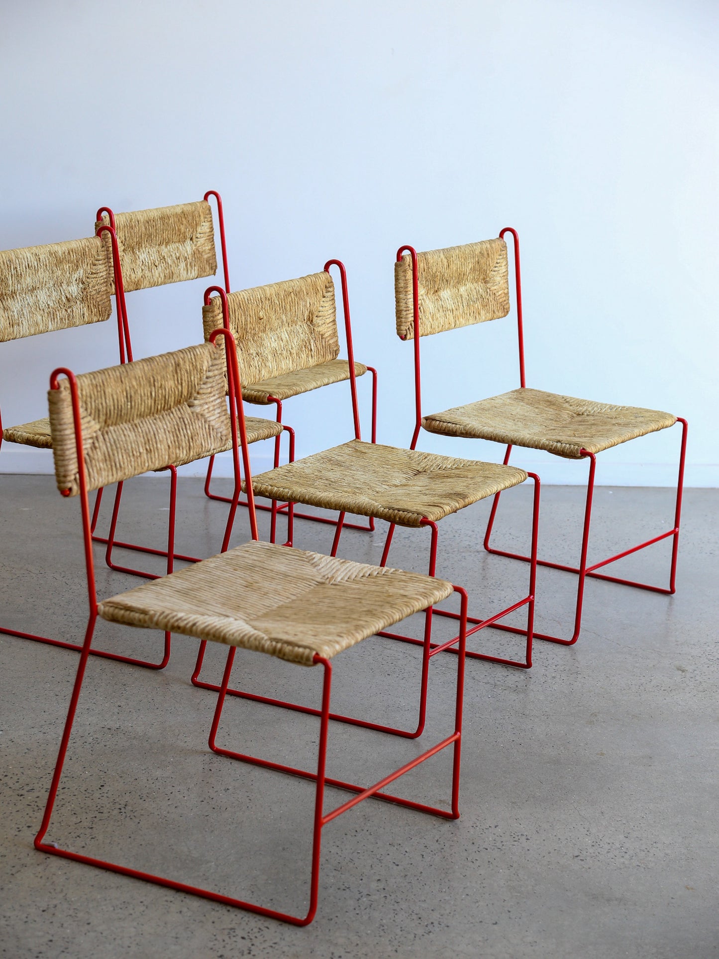 Group of French Pirela Atelier dining chairs, mid-century modern red metal frames with woven rope backs