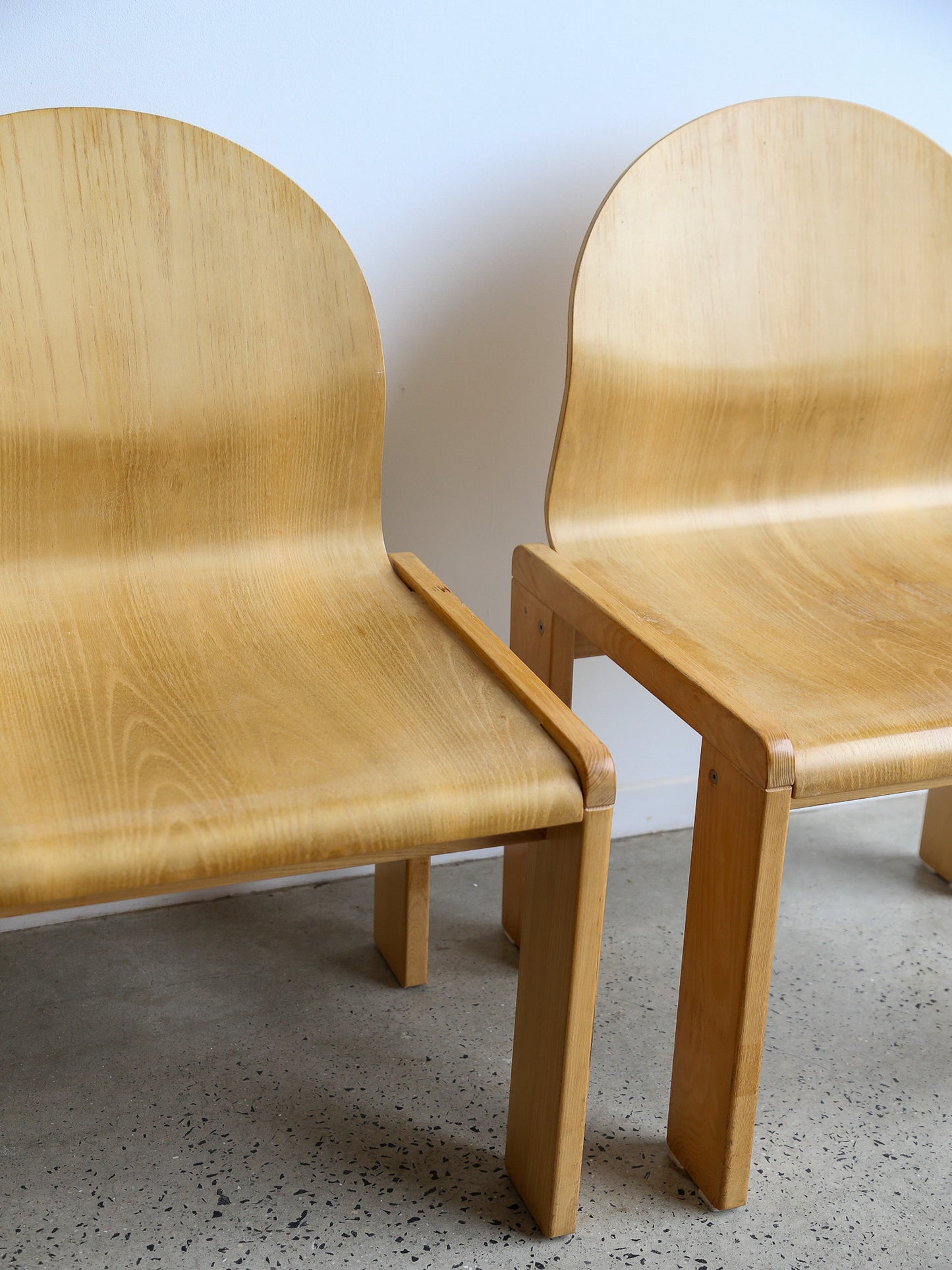 Close-up of Afra & Tobia Scarpa plywood dining chairs, Italy 1970s, showing ergonomic curved seat and backrest.