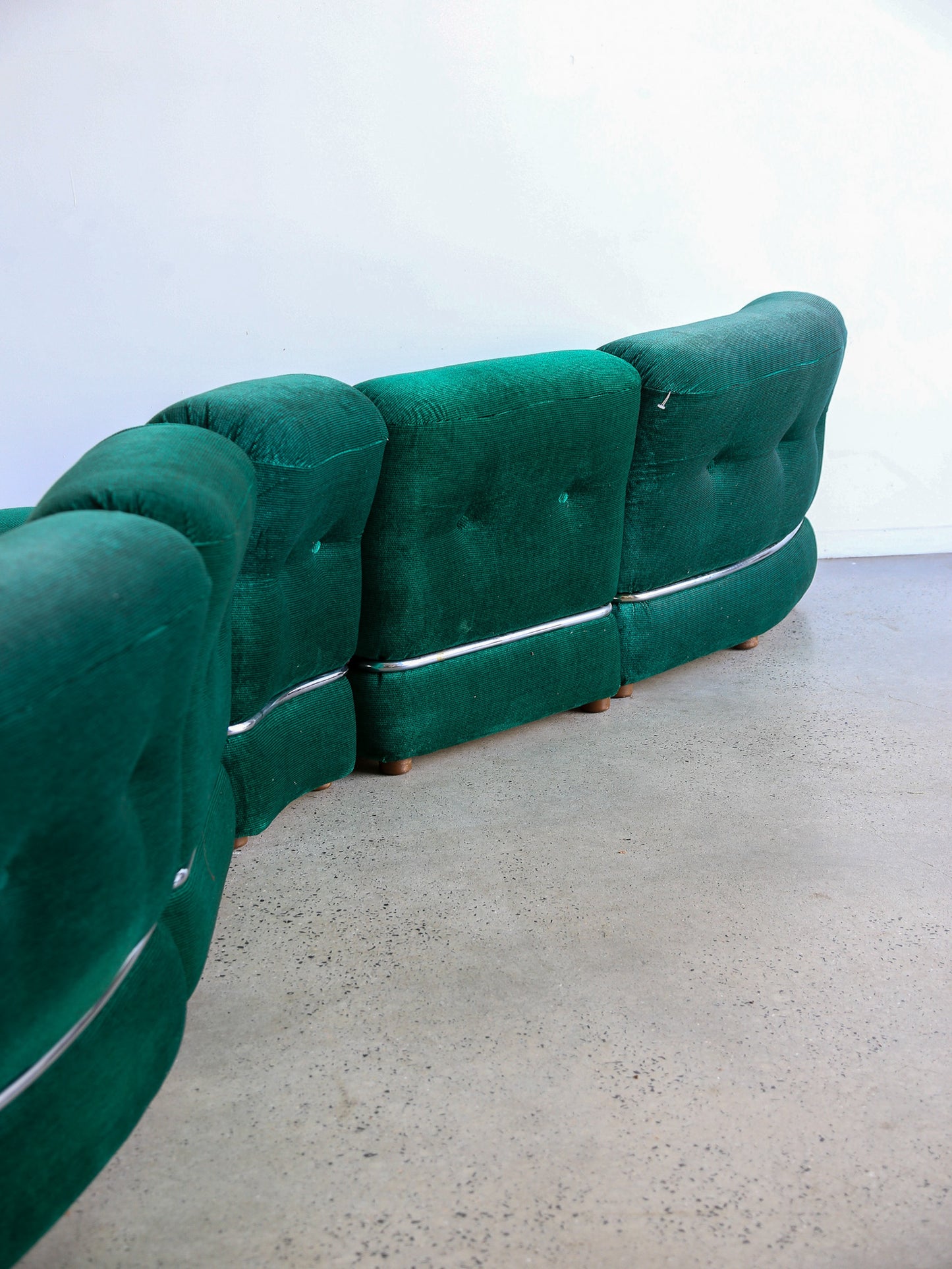 Back view of Adriano Piazzesi emerald green curved sofa with chrome base detail