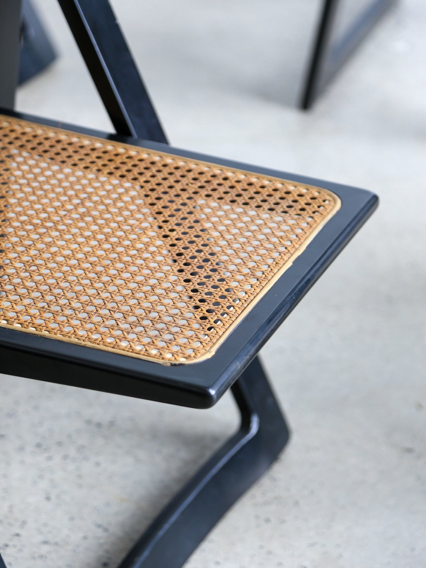 Close view of black lacquered folding chairs with Vienna straw seats, Italian mid-century design by Aldo Jacober