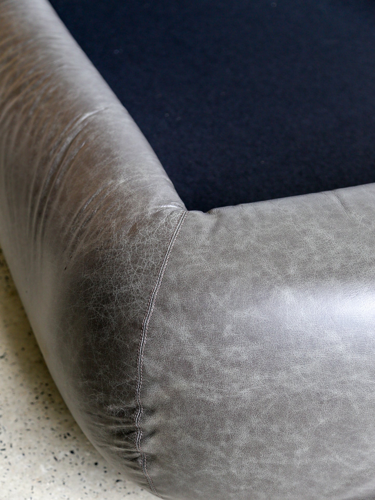 Side view of Gae Aulenti “Tennis” bed in leather, Gavina 1972, showing sculptural curves and plinth detail.