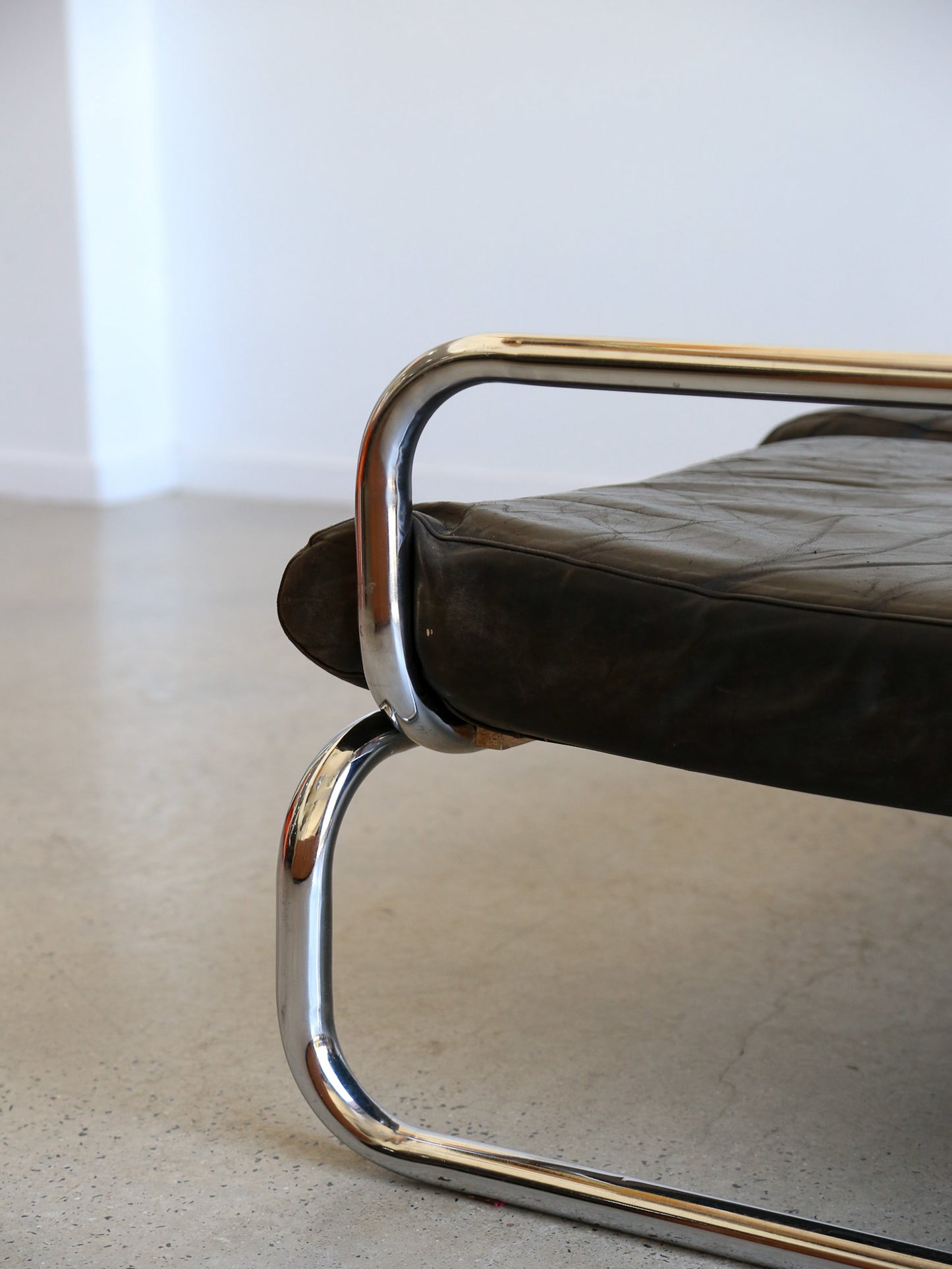 Detail of tubular chrome armrest and leather seat on Rodney Kinsman T-Line sofa