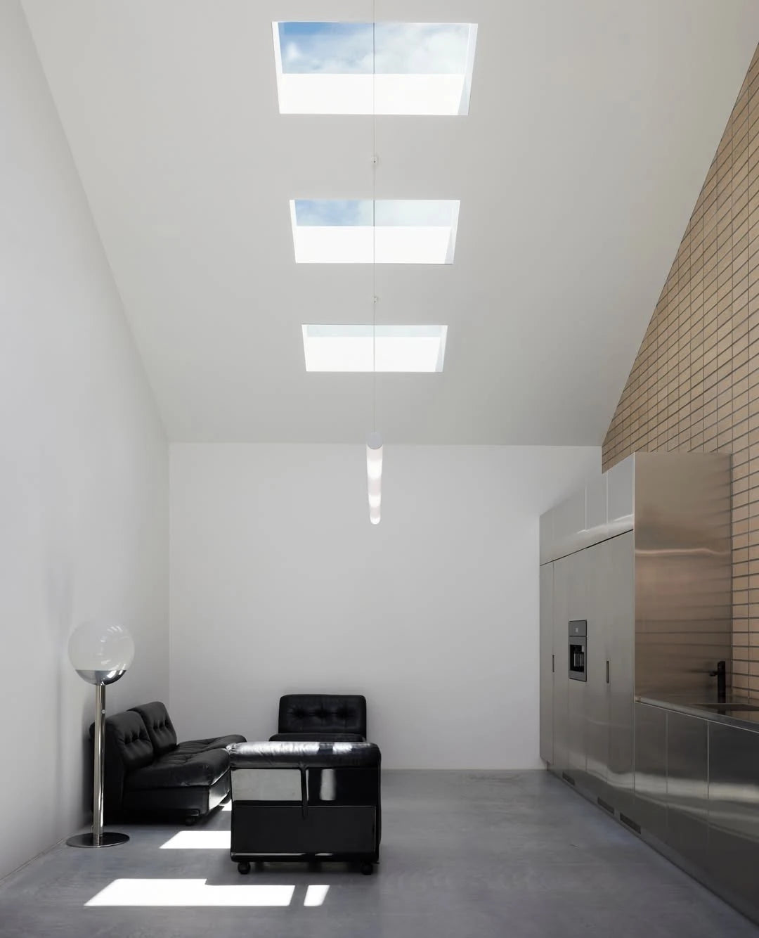 Modern interior with black leather sofa, white walls, and skylights.