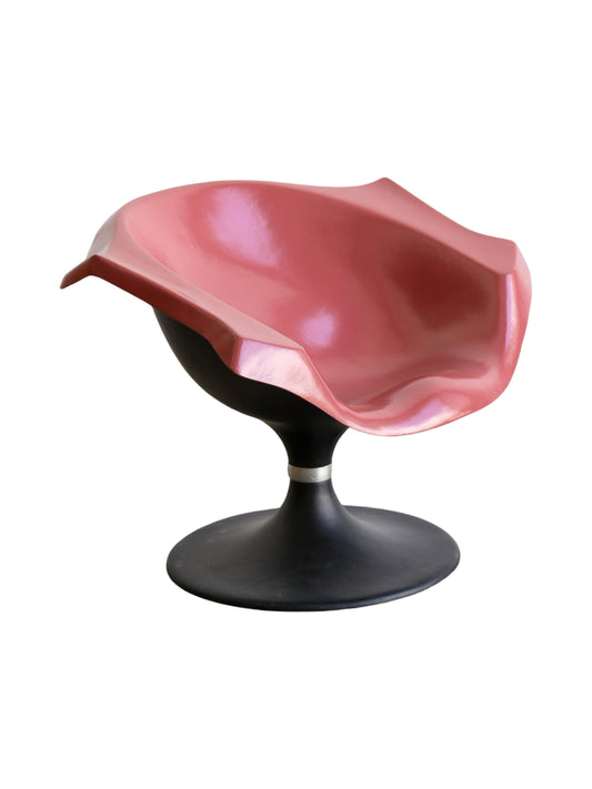 A space age  sculptural chair with a glossy pink fiberglass seat and a black rounded base, exhibiting a mid-century modern or retro-futuristic design.