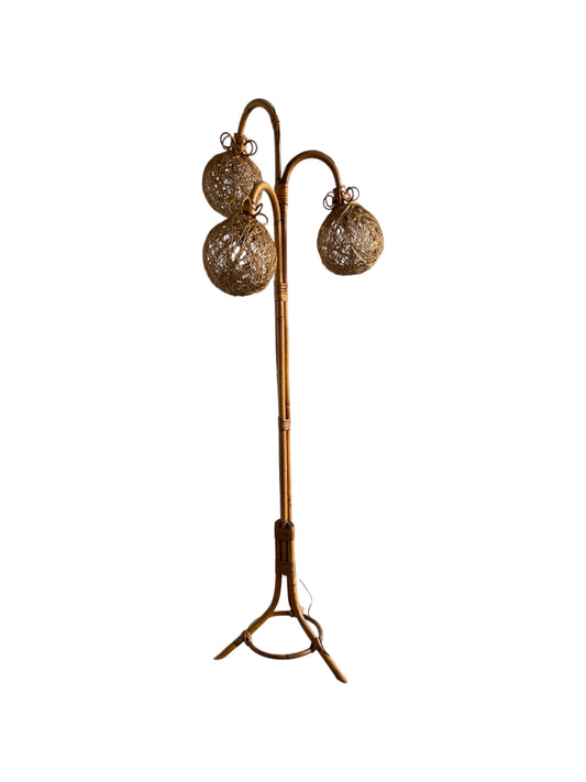A mid-century modern floor lamp with a tripod base and rattan balls woven into the bamboo frame.