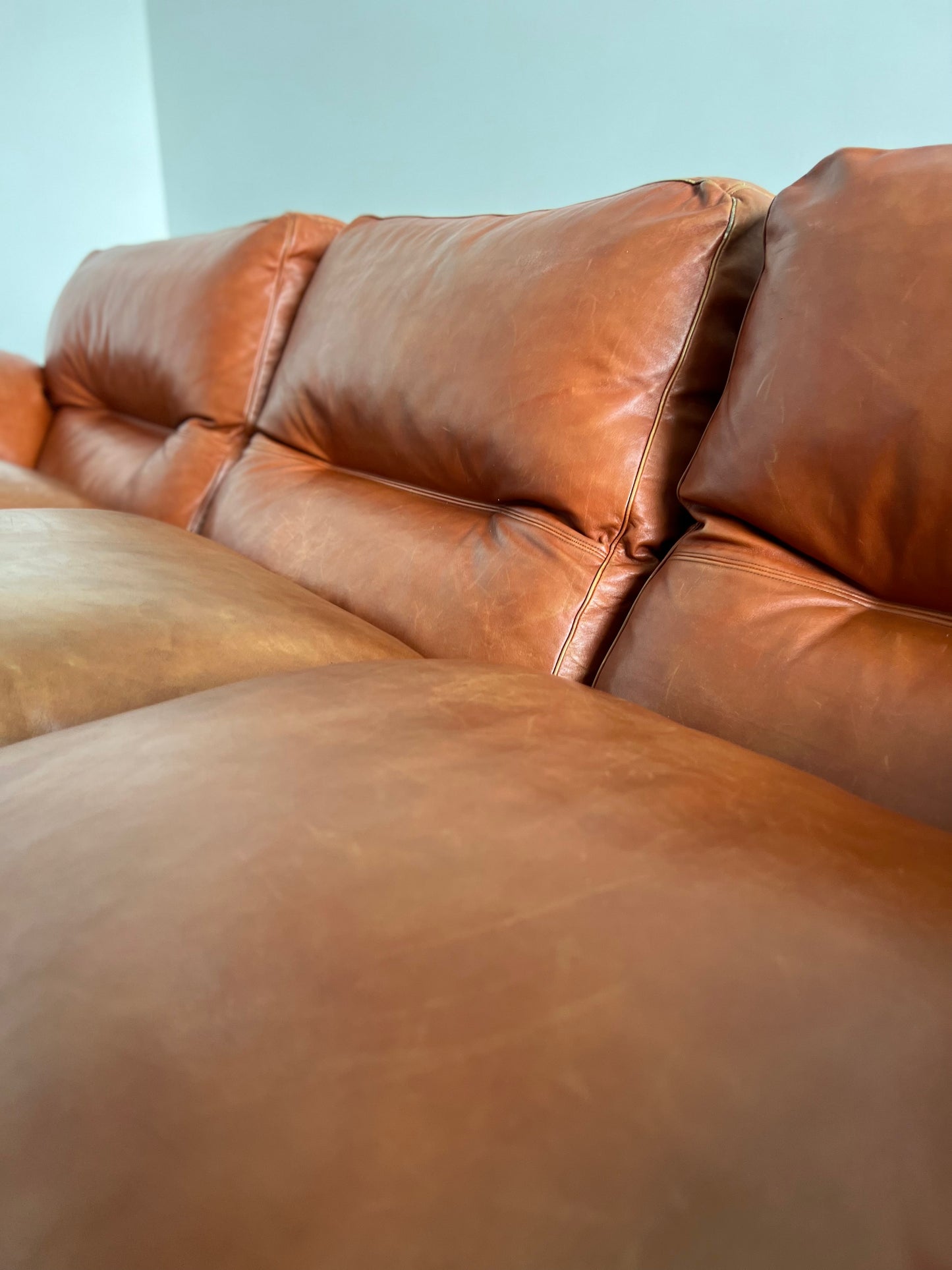 Side angle view of Tito Agnoli’s Poppy sofa for Poltrona Frau, 1960s, showcasing curved armrest and warm cognac leather patina.