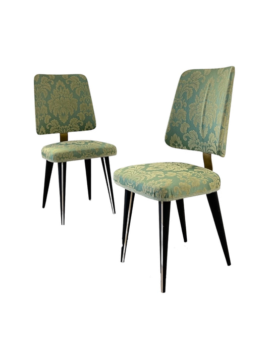 A pair of mid-century modern dining chairs with upholstered seats and backrests, featuring a floral pattern, metallic frames, and wooden legs.