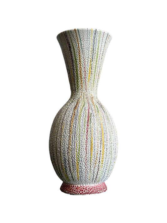 A multicolored hand made ceramic vase with a geometric pattern and a red base.