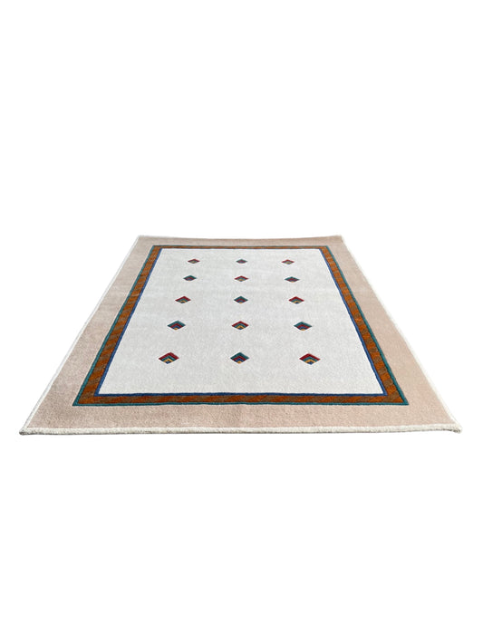 A cream-colored rectangular wool rug with a geometric pattern consisting of diamonds and a border detail.
