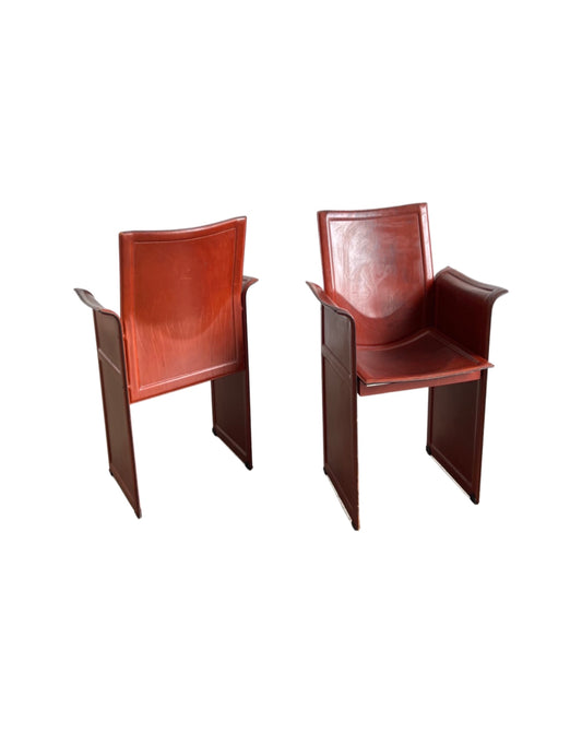 A pair of brown 'Korium' leather armchairs designed by Tito Agnoli for Matteo Grassi, featuring a full leather upholstery and wooden frame.
