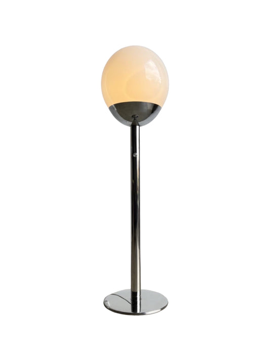 floor lamp by Pia Guidetti for Luci Milano  with a chrome base and an opaline glass ball shade, standing upright against a white background.
