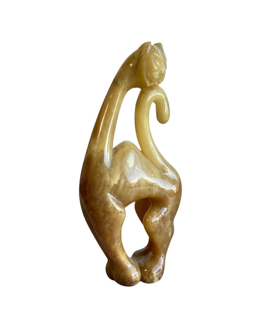 A vintage sculpture of a cat made from amber onyx stone, displaying a translucent, amber-like quality.