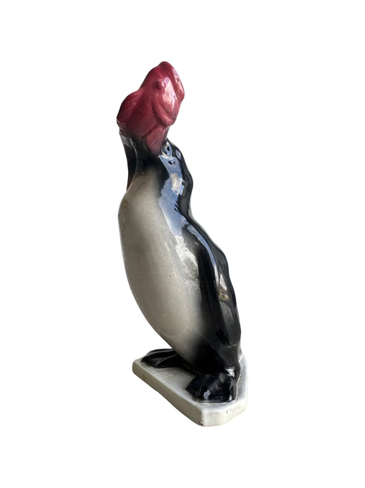 A ceramic figurine of a black and white penguin on a base, with a glazed finish.