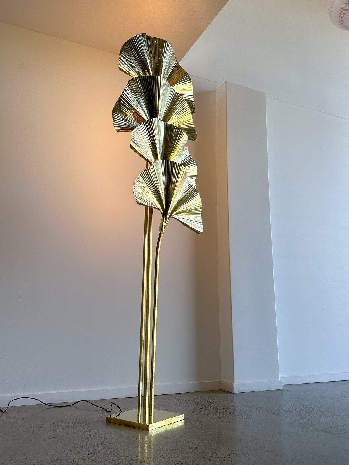 Gold leaf-shaped floor lamp against a white wall