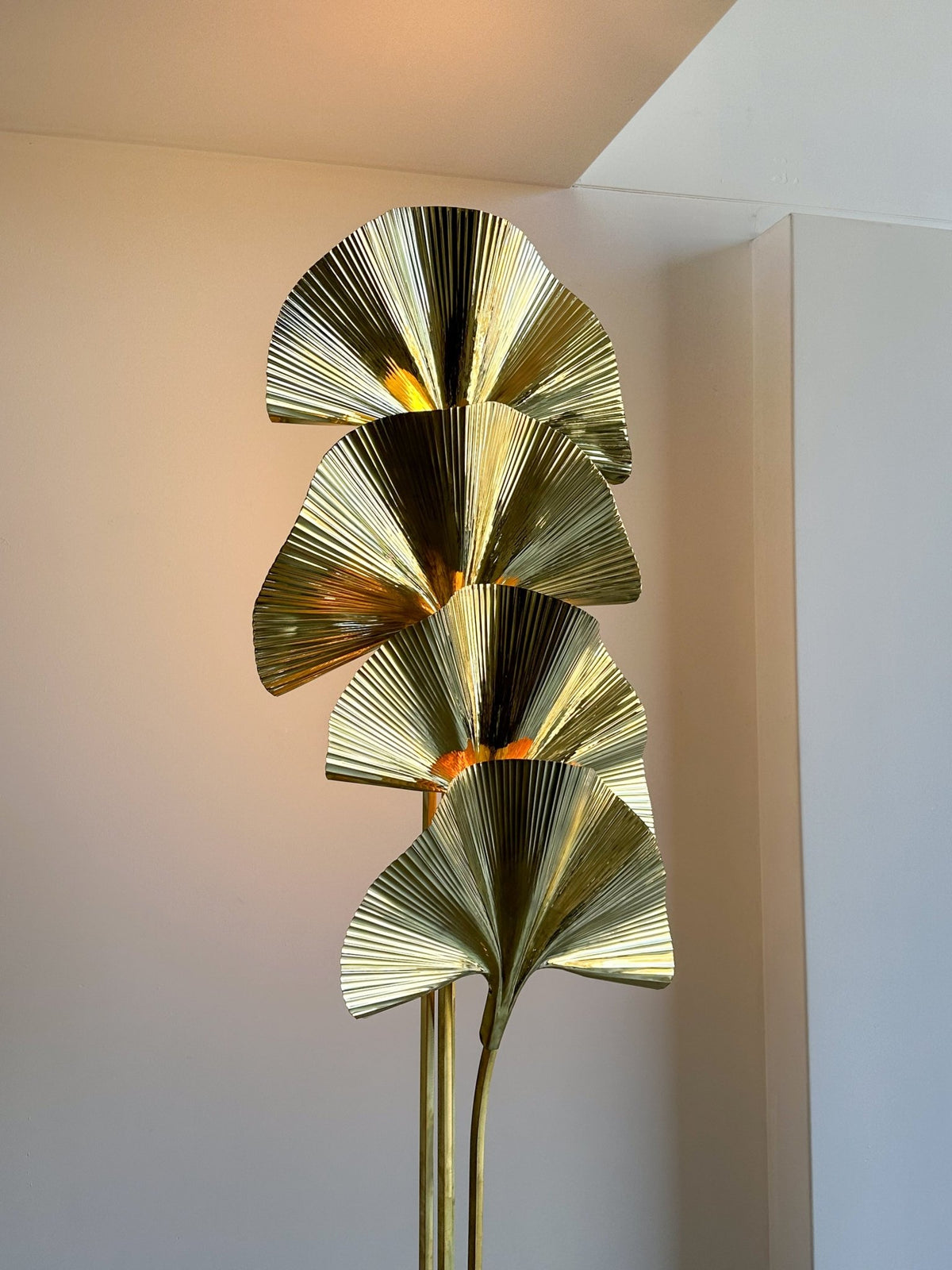 Decorative wall sconce with gold leaf-like design on a neutral wall.