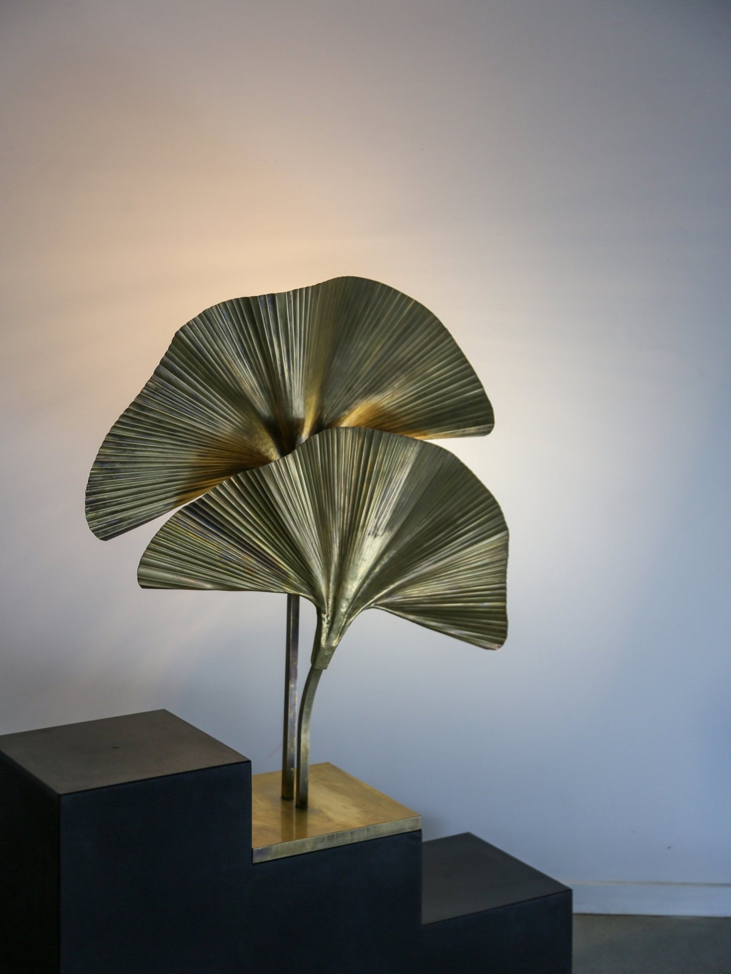 Decorative lamp with leaf design on a black pedestal against a plain background