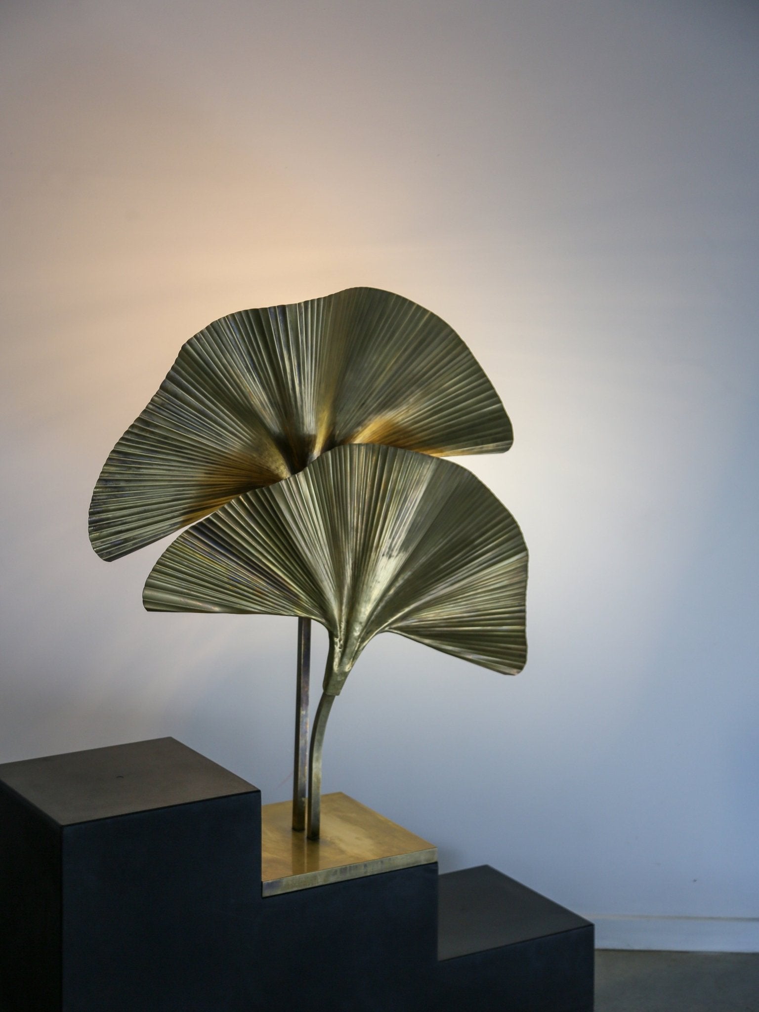 Decorative lamp with leaf design on a black pedestal against a plain background