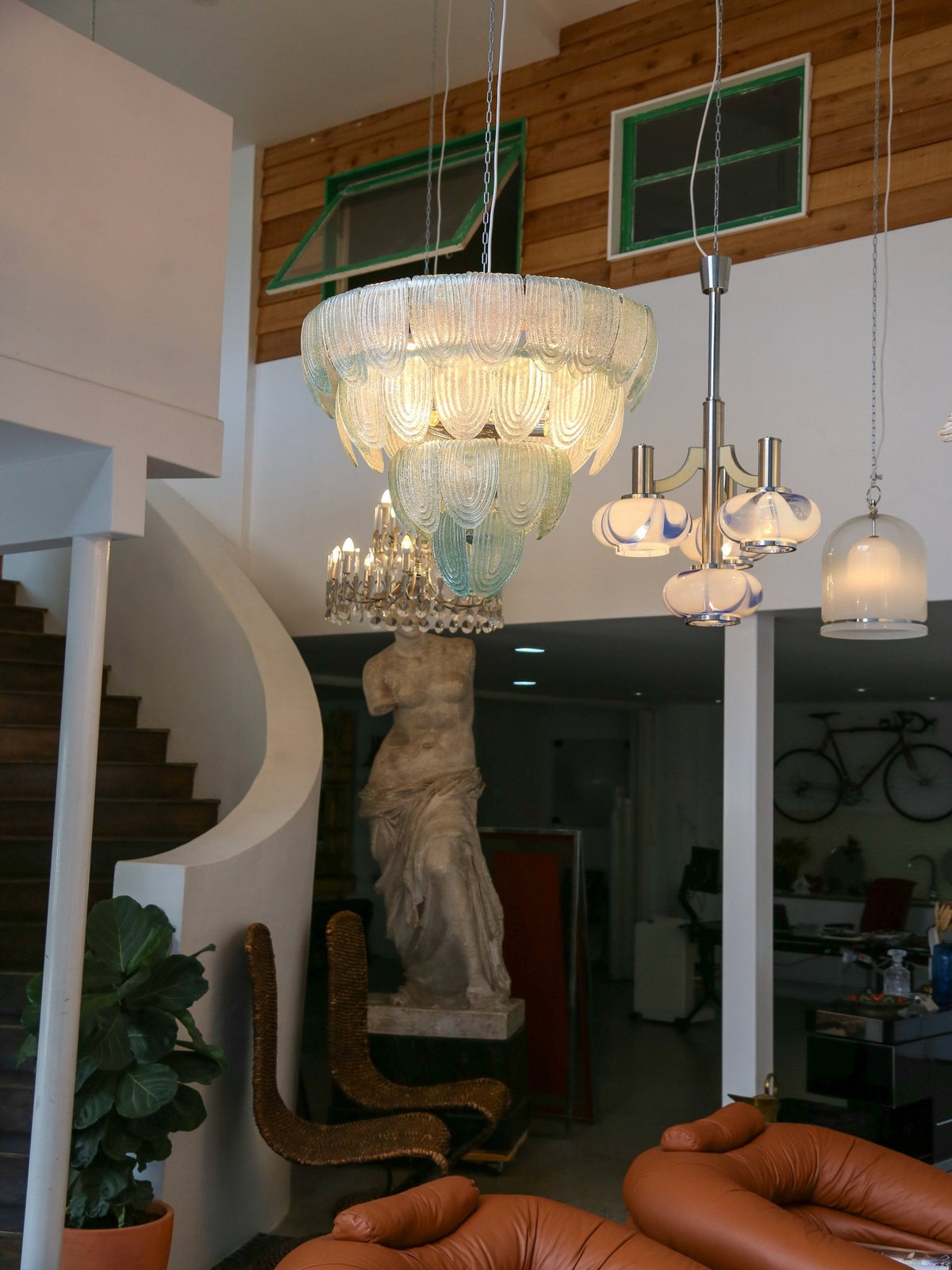 Chandelier hanging in a room with a staircase and decor elements.