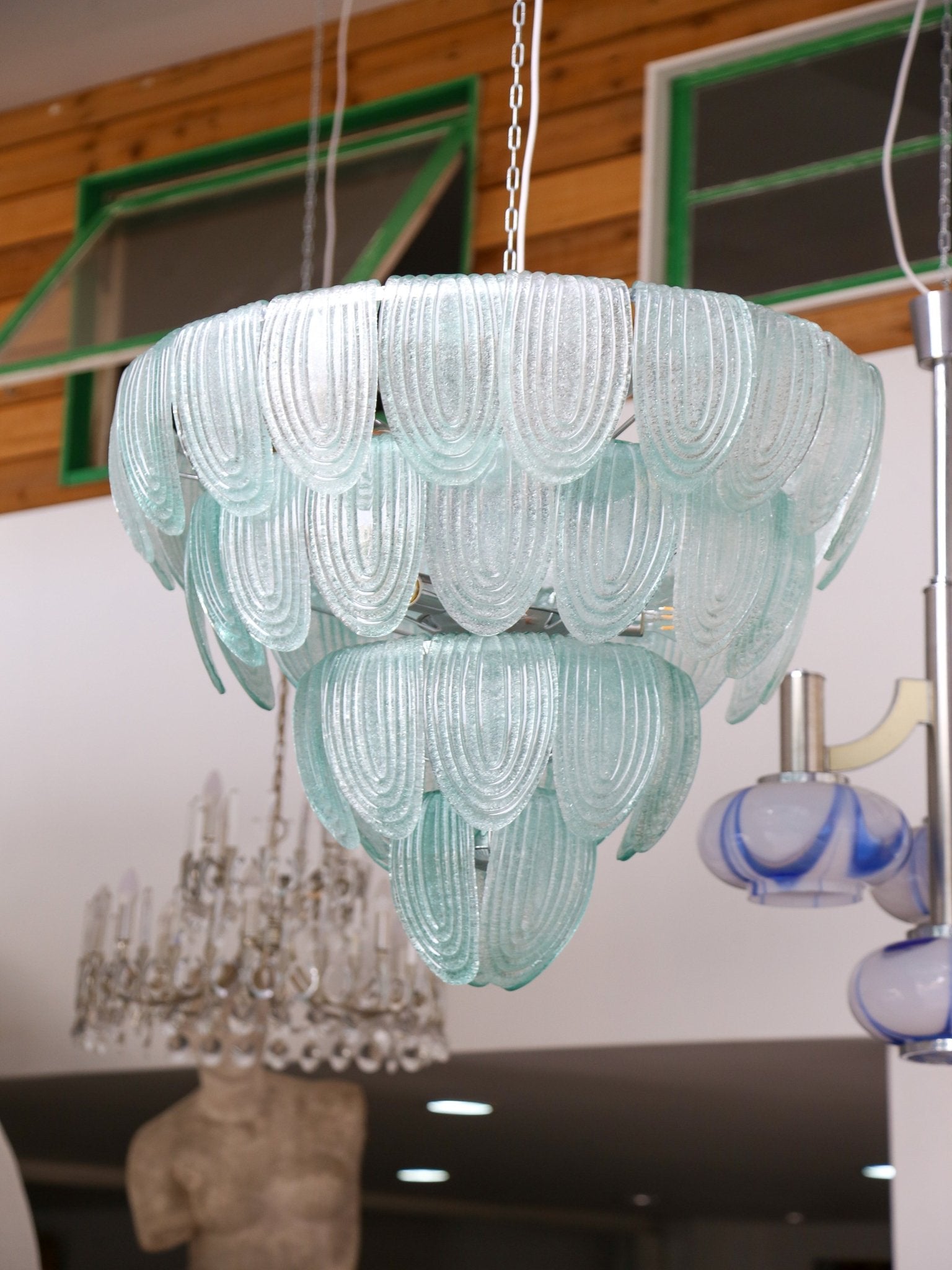 Turquoise glass chandelier hanging in a room with a blurred background