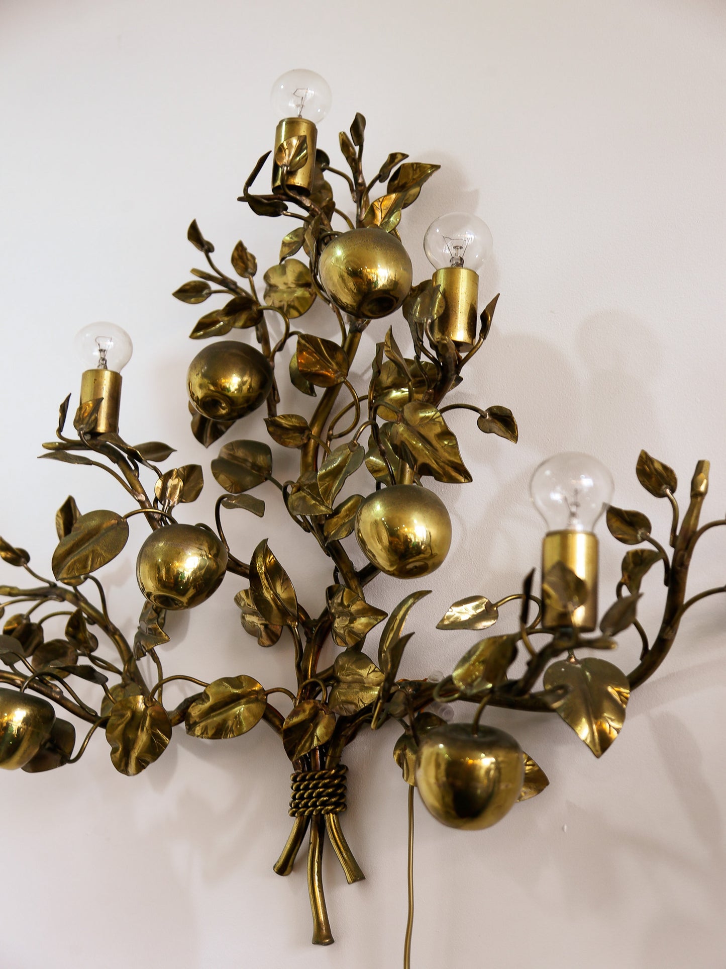 Decorative wall sconce with gold leaves and fruit design on a white background