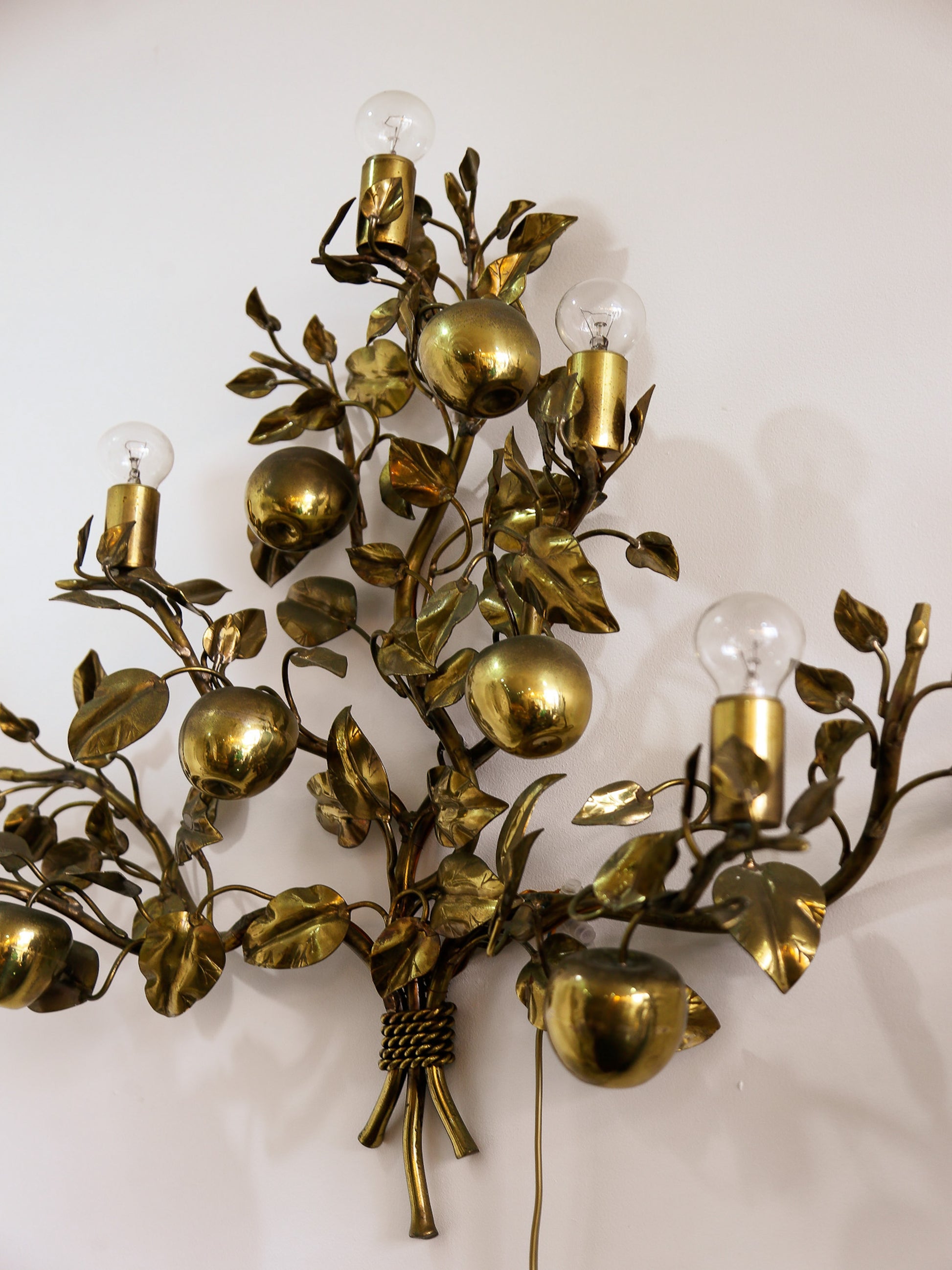 Decorative wall sconce with gold leaves and fruit design on a white background