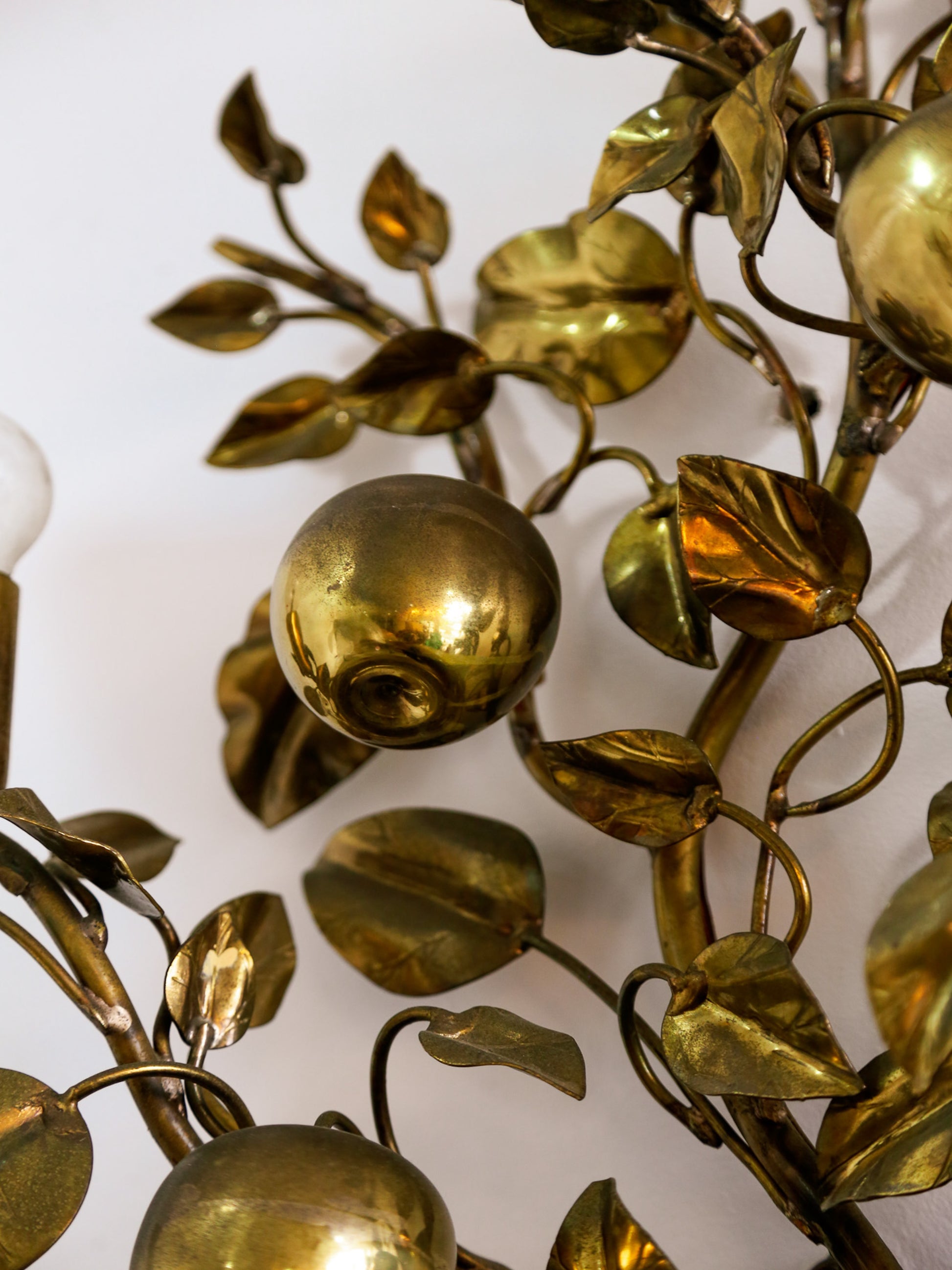 Close-up of a decorative brass wall piece with leaves and spherical elements.