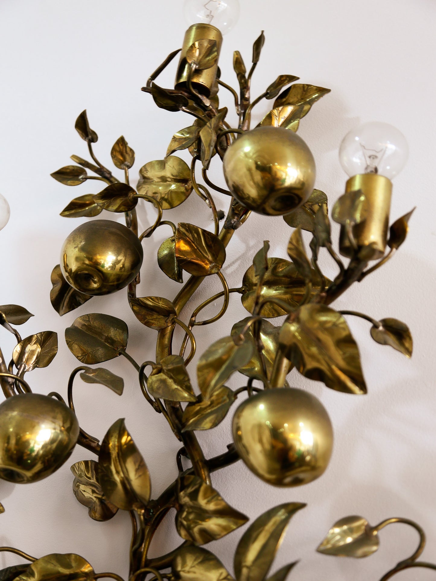 Decorative brass sconce with apple and leaf design on a white background