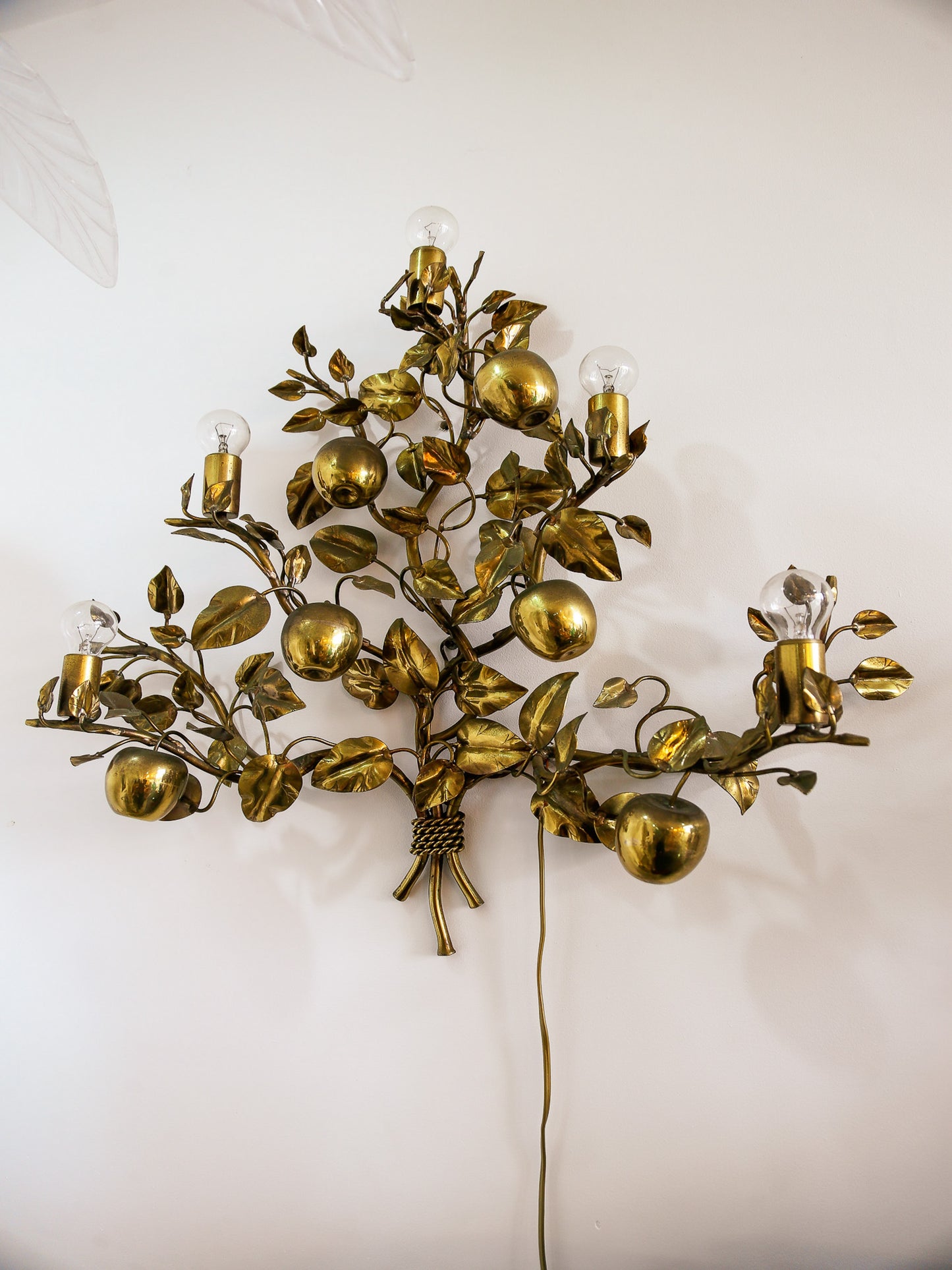 Decorative wall sconce with gold leaves and fruit design on a white background