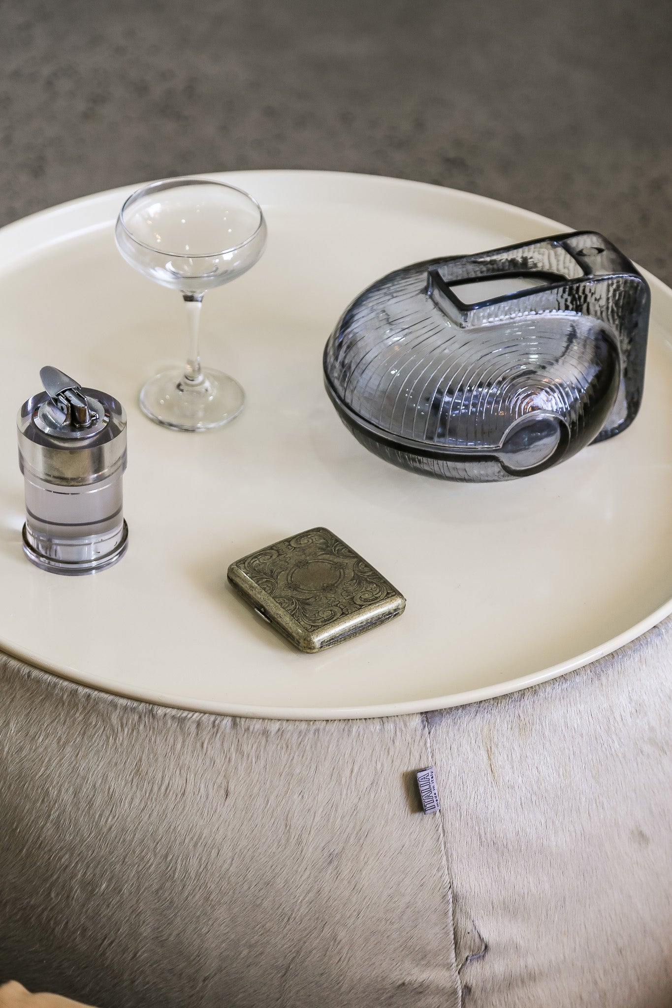 Decorative items including a glass bowl, candle, and small square object on a round surface.