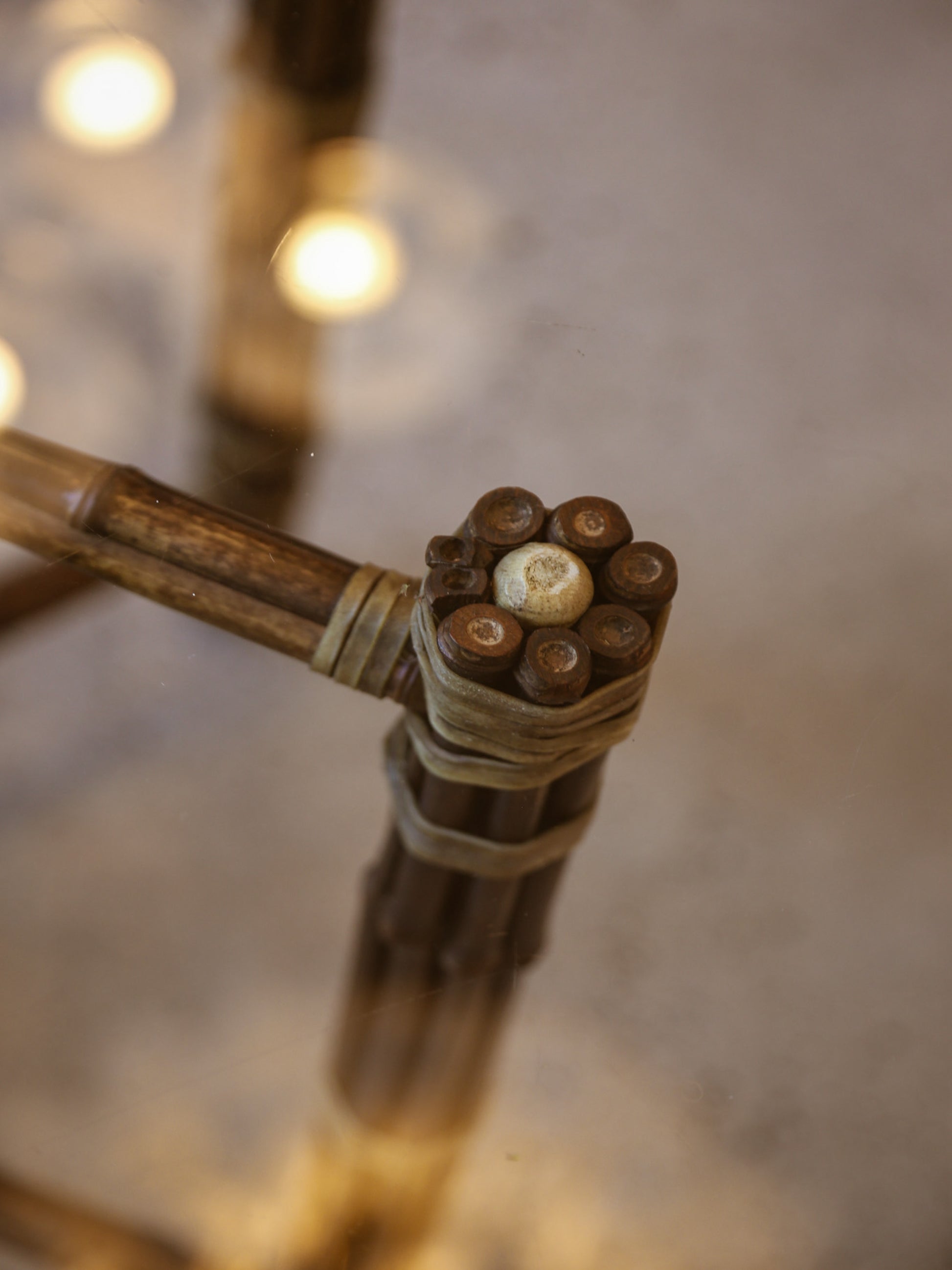 Close-up of a bamboo stick with small stones or pebbles attached, on a blurred background.