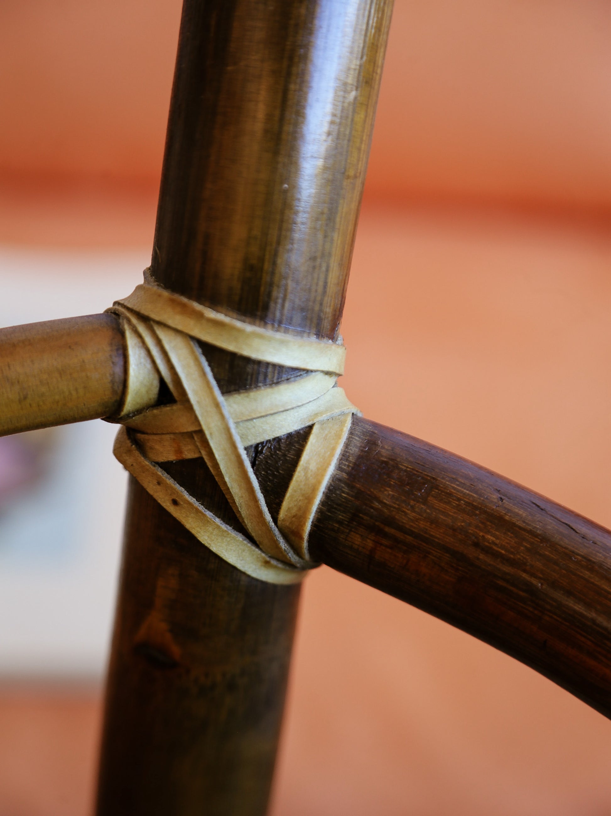 Close-up of a bamboo stick with a woven band against a blurred orange background