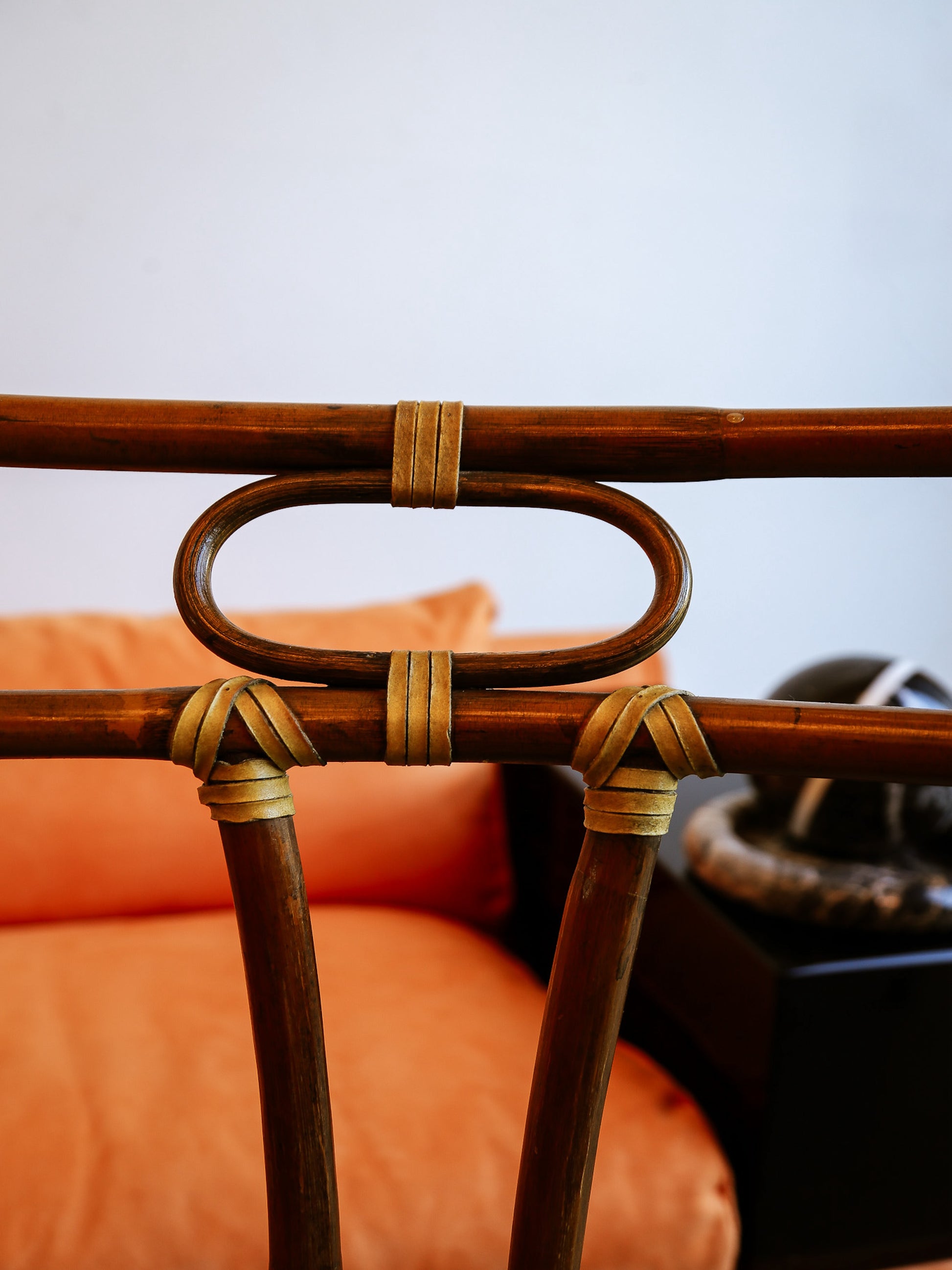 Close-up of a wicker chair with orange cushion against a blurred background