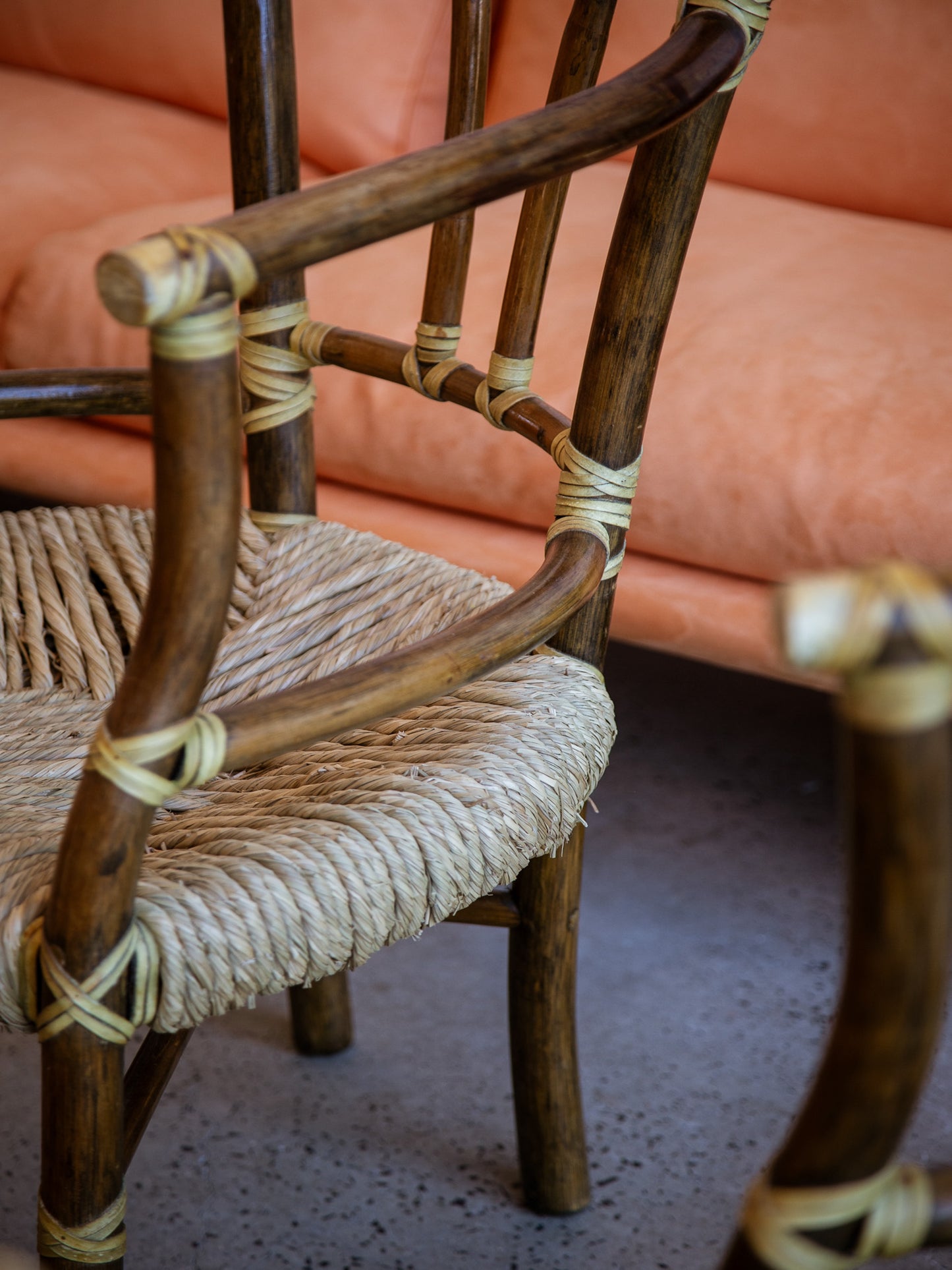Wooden chair with woven seat and backrest in front of a pink sofa.