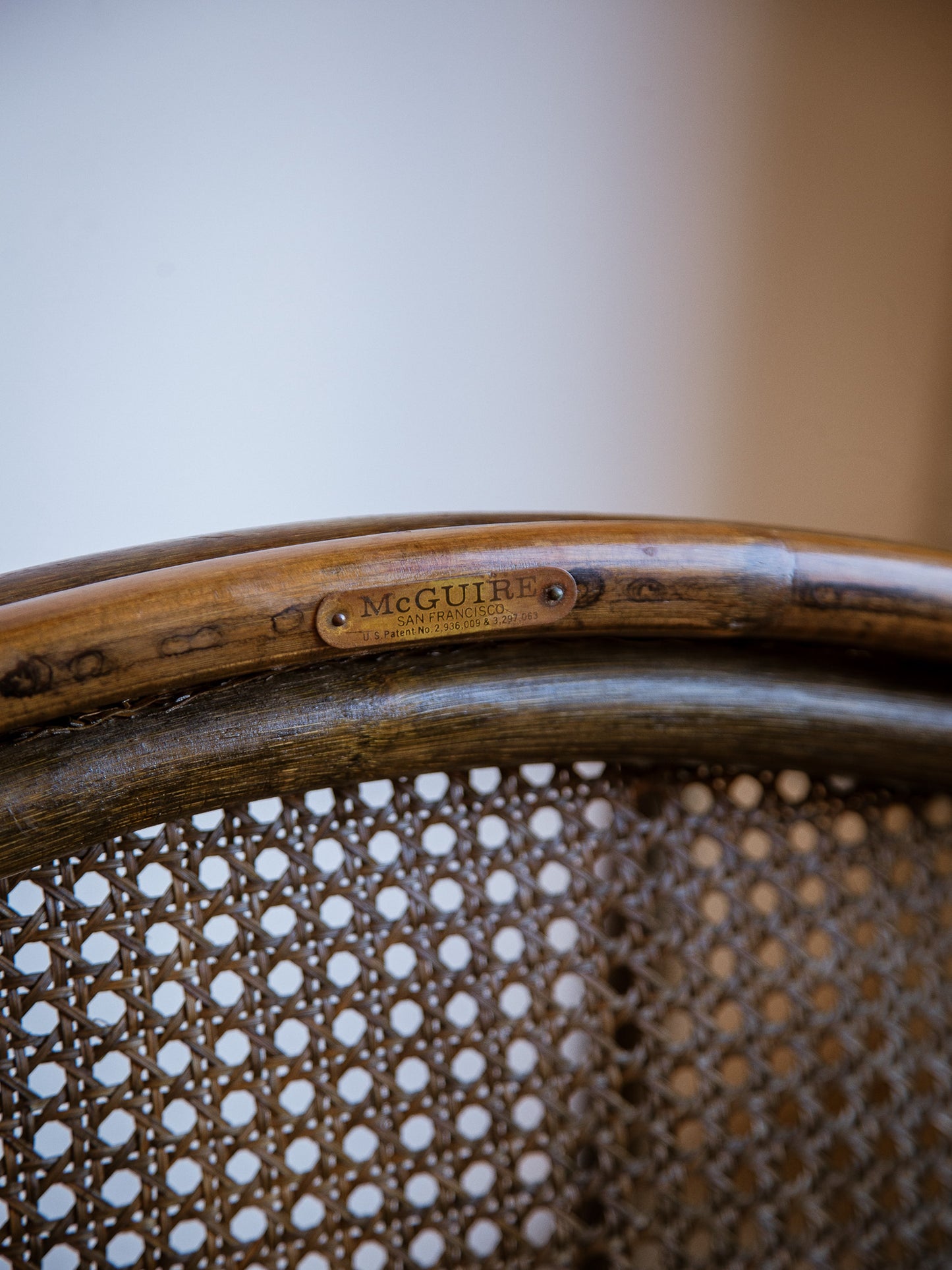 Close-up of a wicker chair with 'McGuire' branding on a blurred background