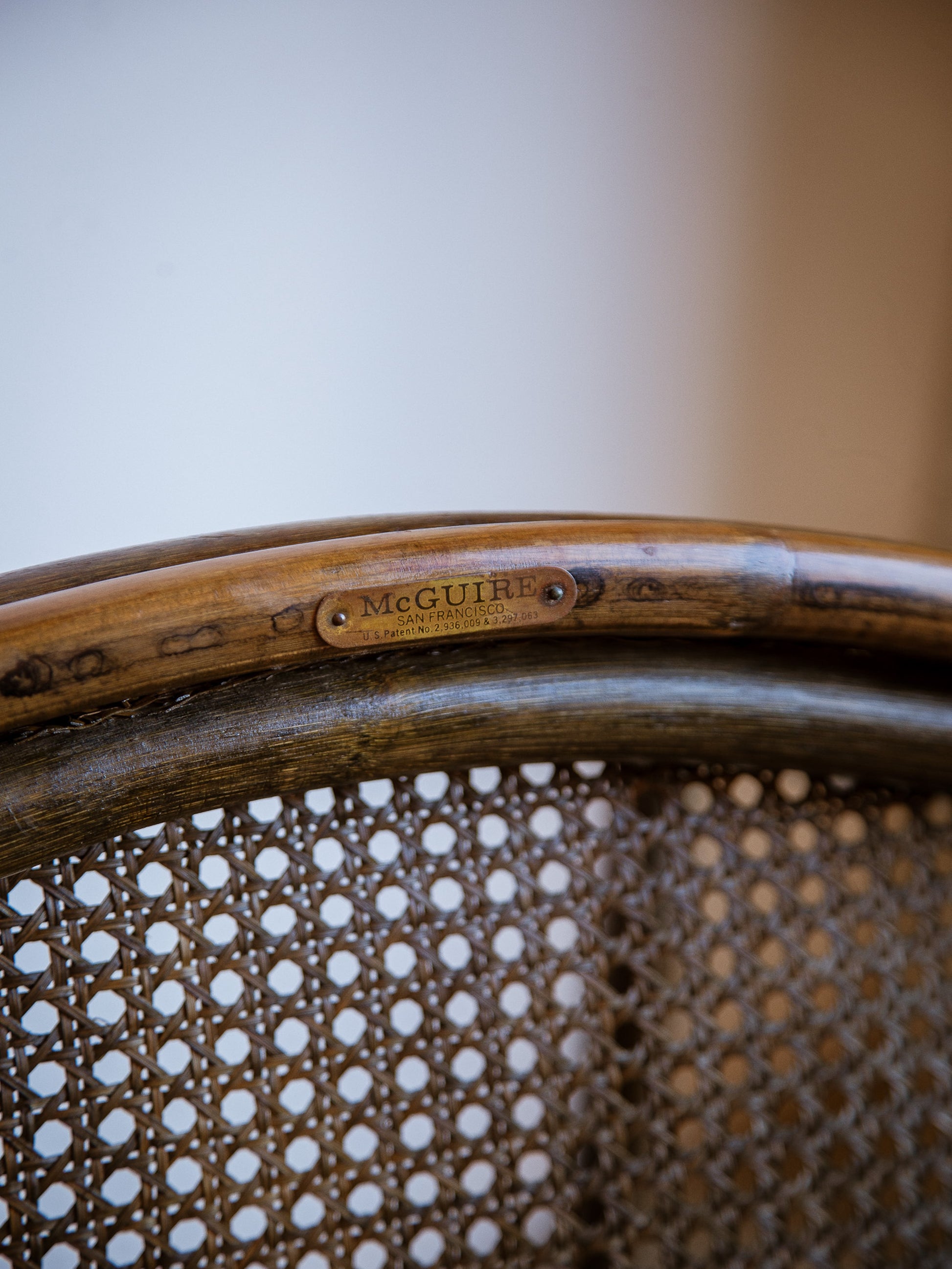 Close-up of a wicker chair with 'McGuire' branding on a blurred background