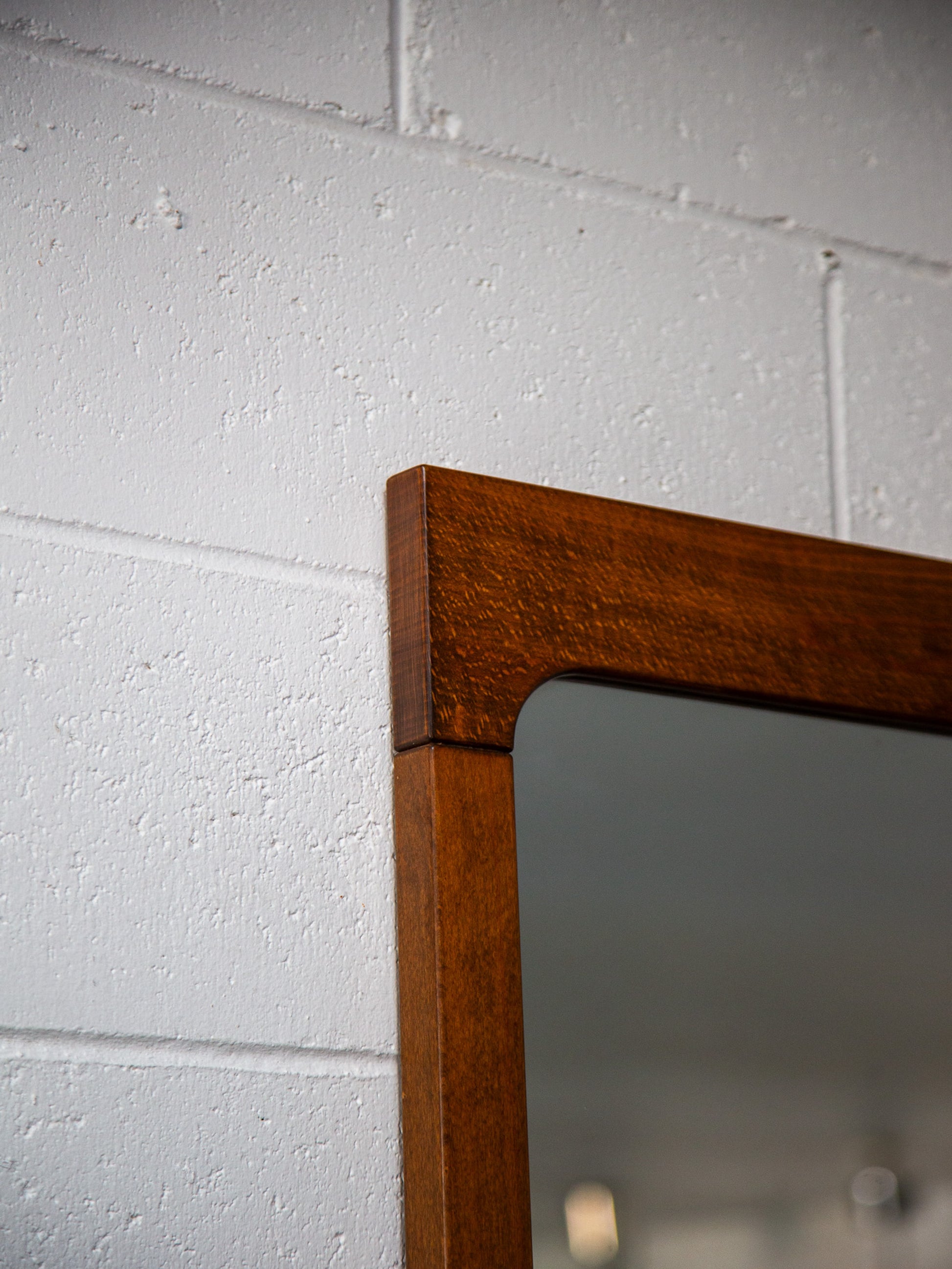 Wooden-framed mirror on a white brick wall