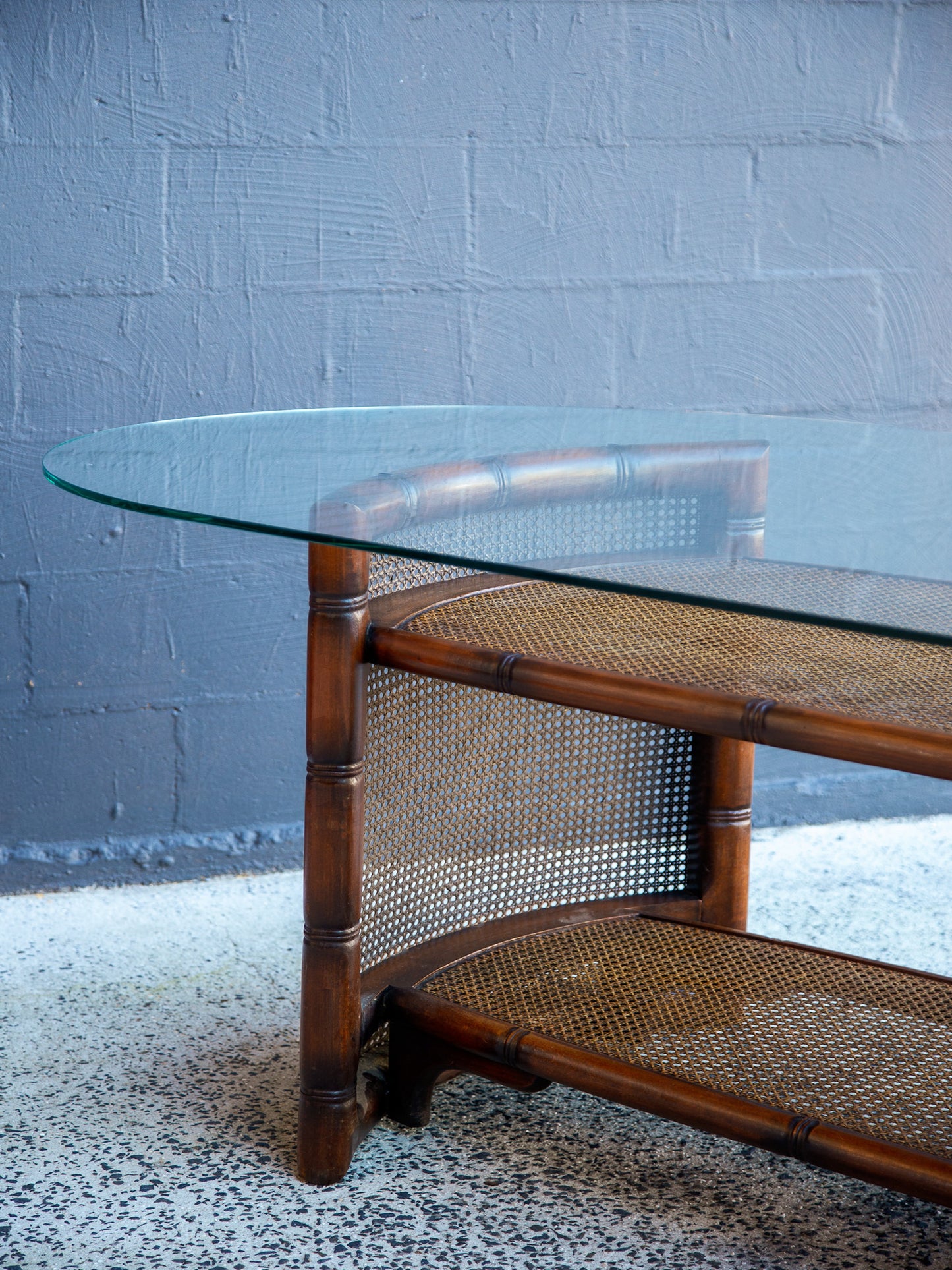Glass-top table with wicker base against a textured wall.