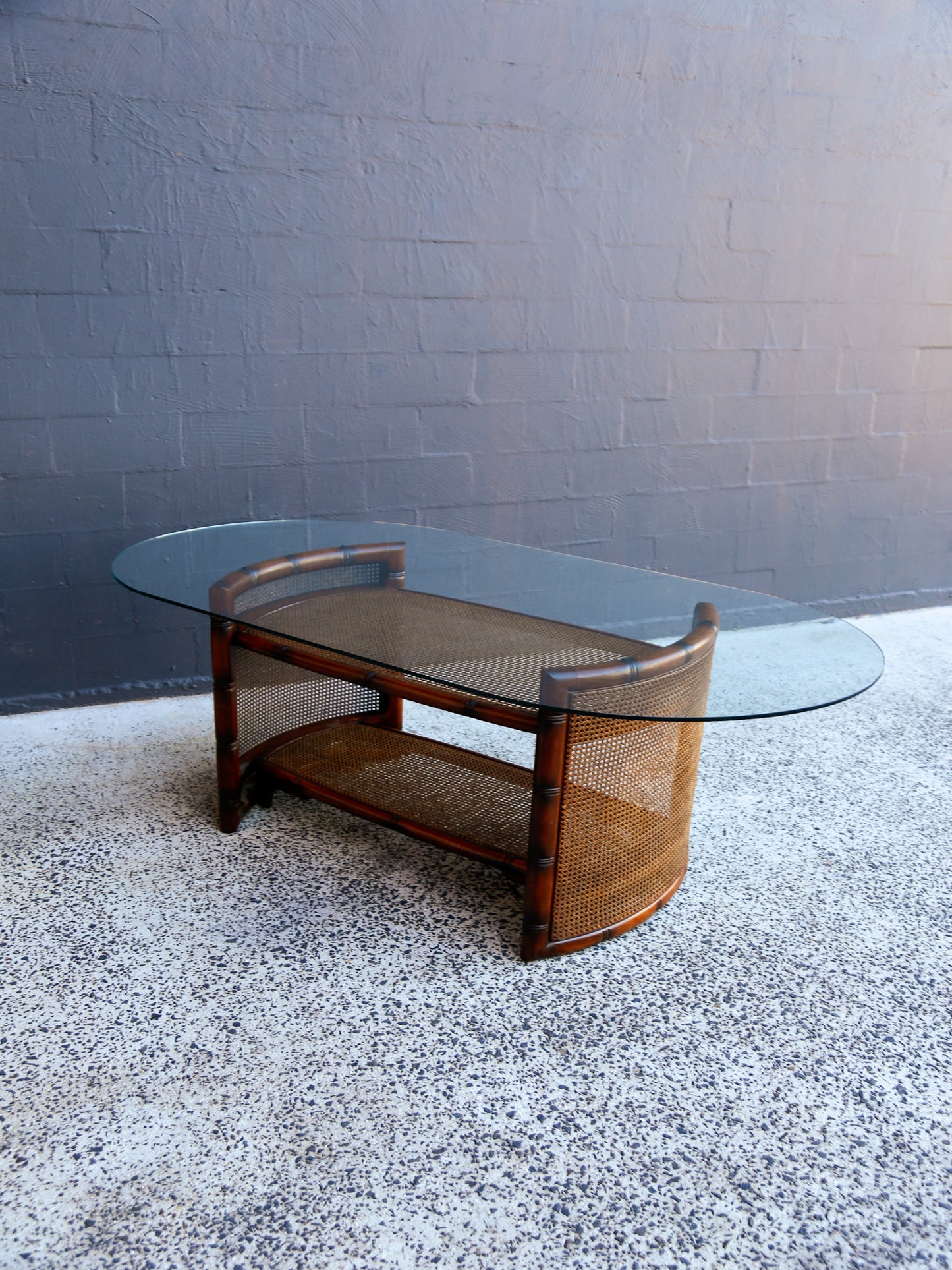 Glass coffee table with wooden frame on a textured floor against a gray wall