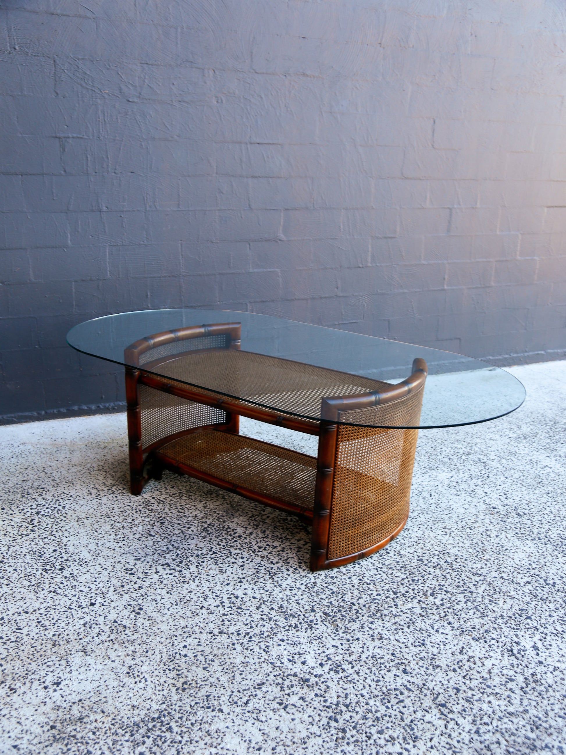 Glass coffee table with wooden frame on a textured floor against a gray wall