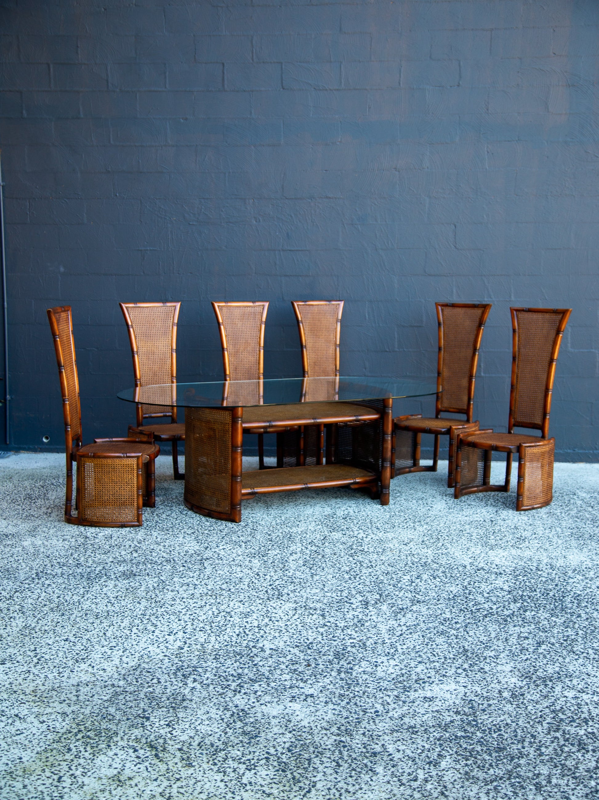 Dining table set with six chairs against a blue wall.