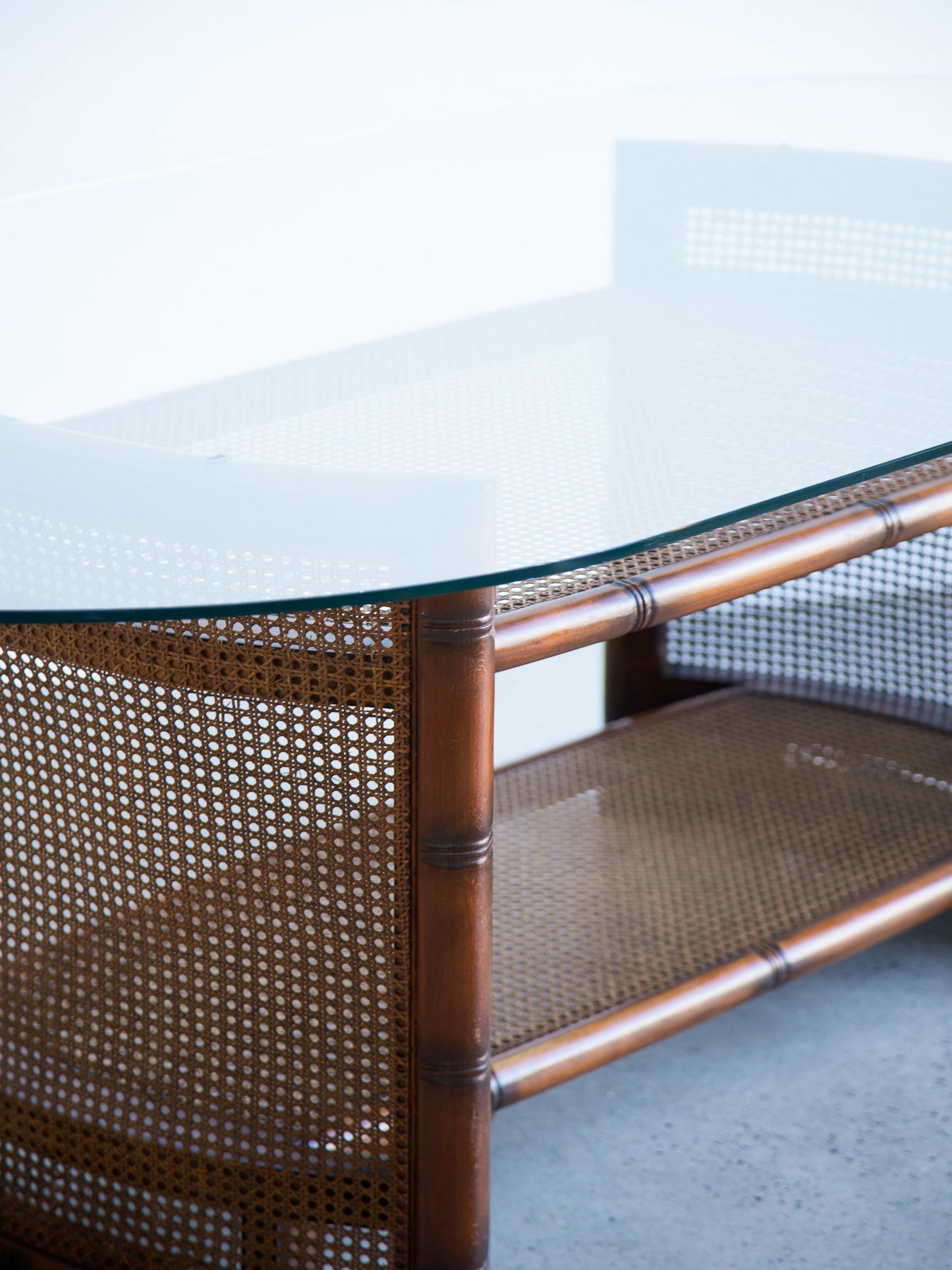 Glass-top coffee table with wicker frame on a light background