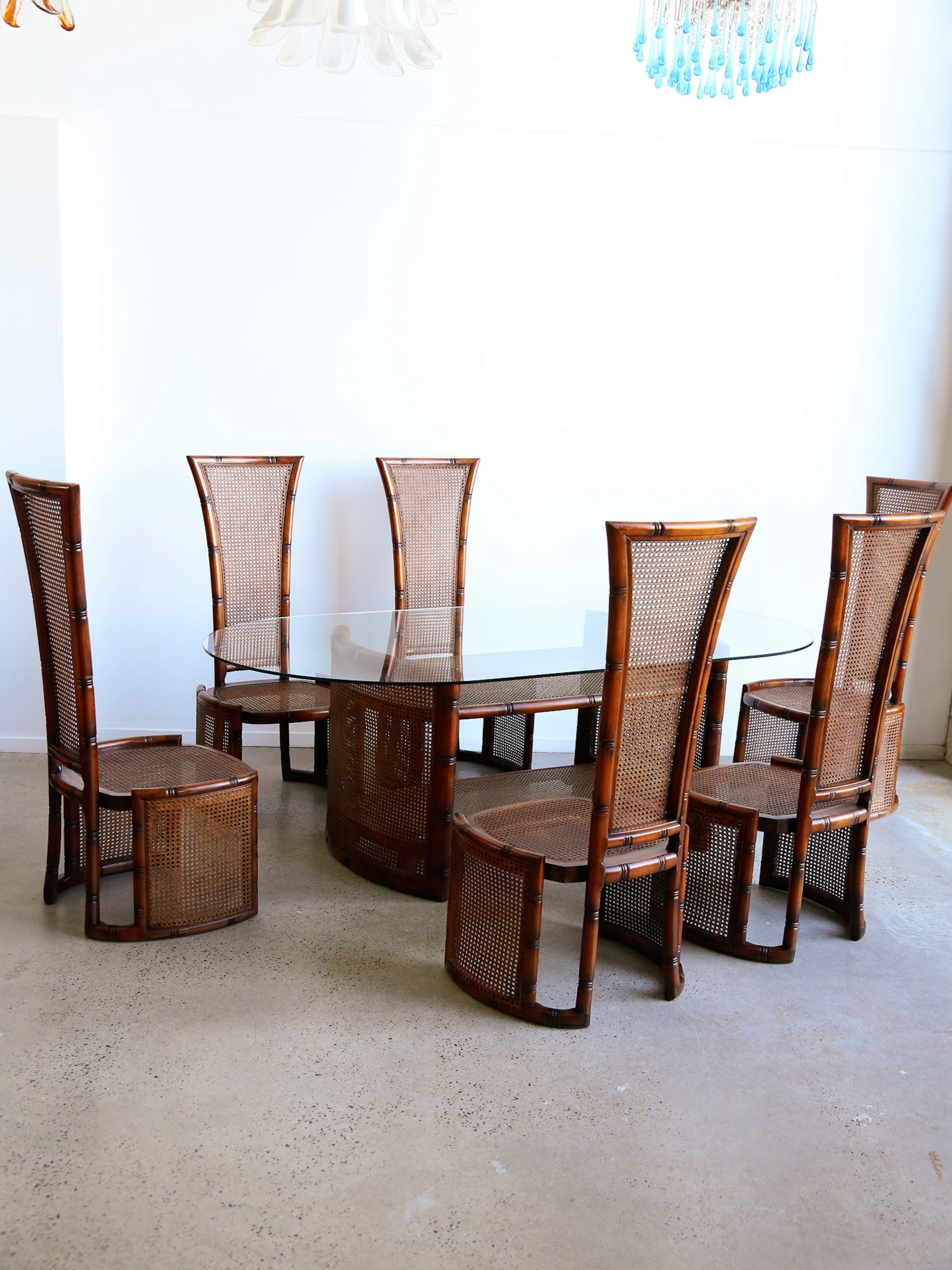 Dining room set with wooden chairs and a glass table on a light-colored floor.