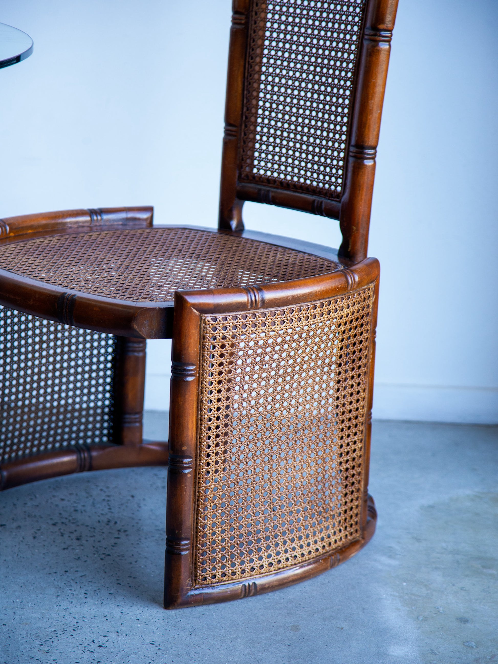 Wooden chair with wicker back and seat on a concrete floor.