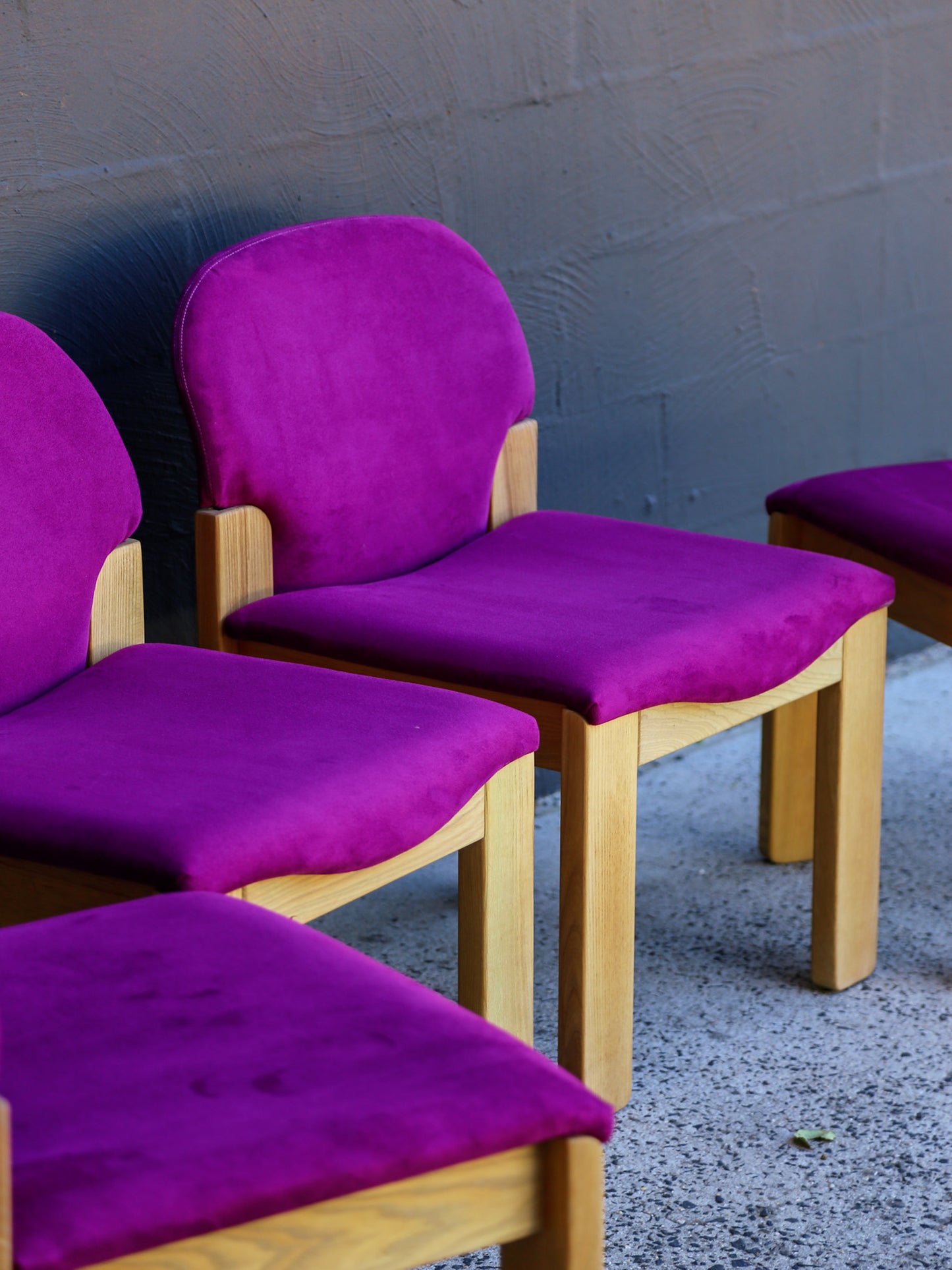 Purple cushioned chairs against a gray wall.